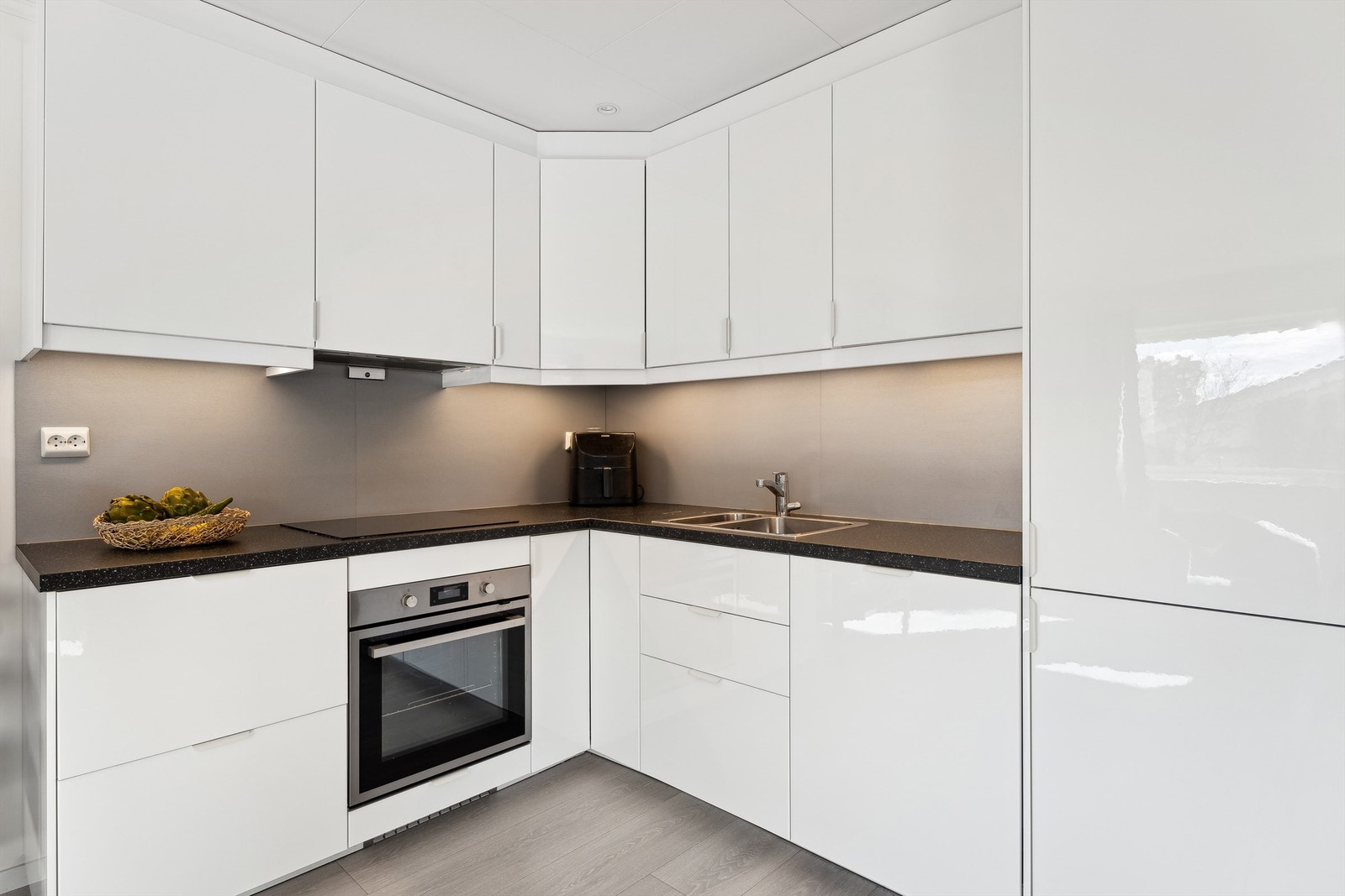 Kjøkken i uteleiedelen ligger i åpen løsning mot stuen og har hvite, glatte fronter samt en laminert benkeplate med nedfelt oppvaskkum. Det er godt utstyrt med integrerte hvitevarer. Galleribilde