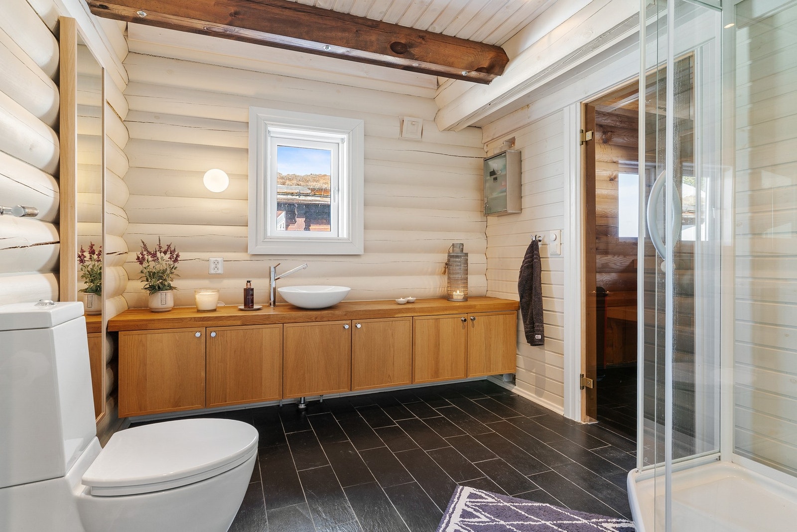 Hyttas andre bad har flislagt gulv, tømmer- og panelvegger, samt synlige åser i taket. Galleribilde