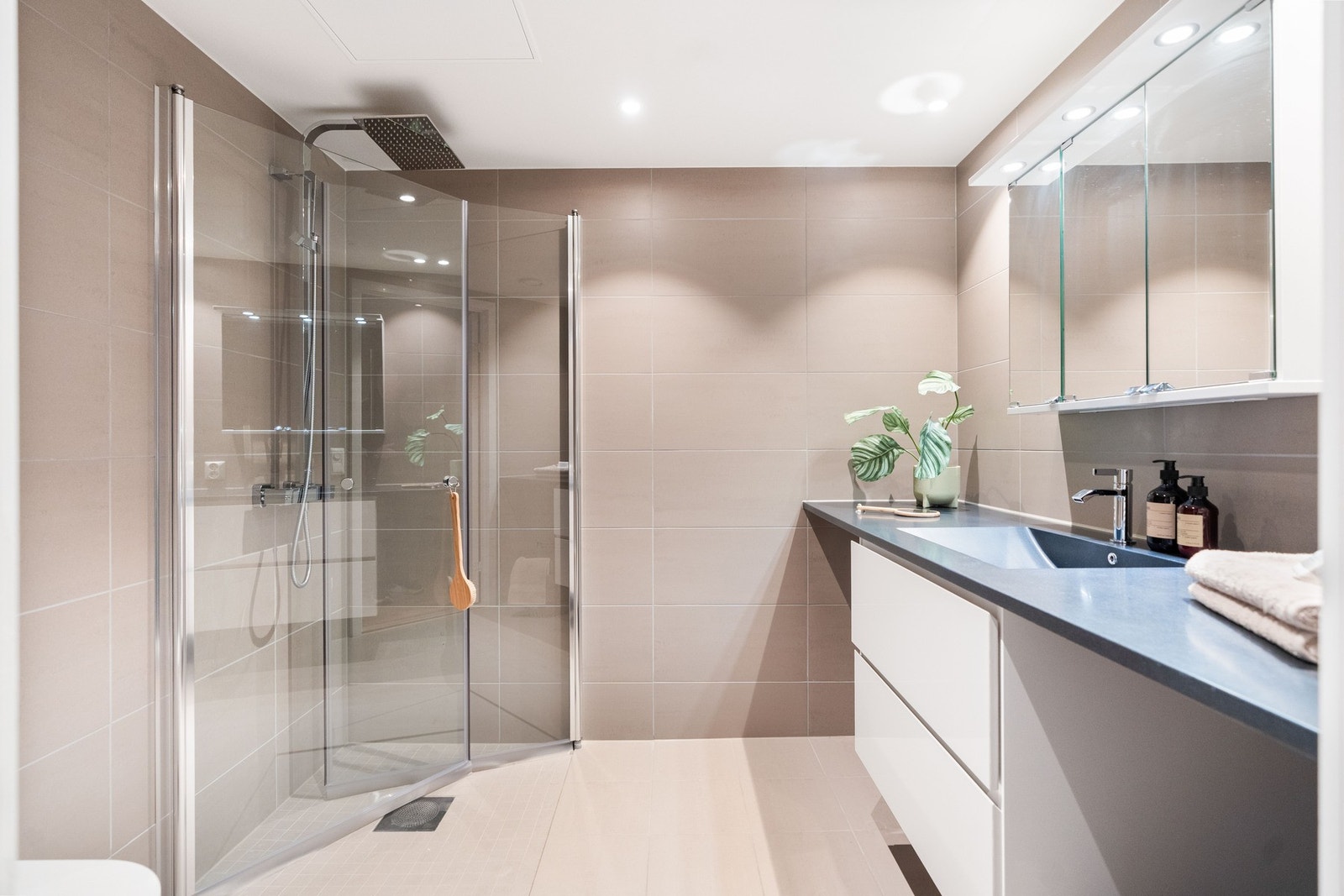 Baderom med fliser i varme beige nyanser som gir et elegant og lyst preg Galleribilde