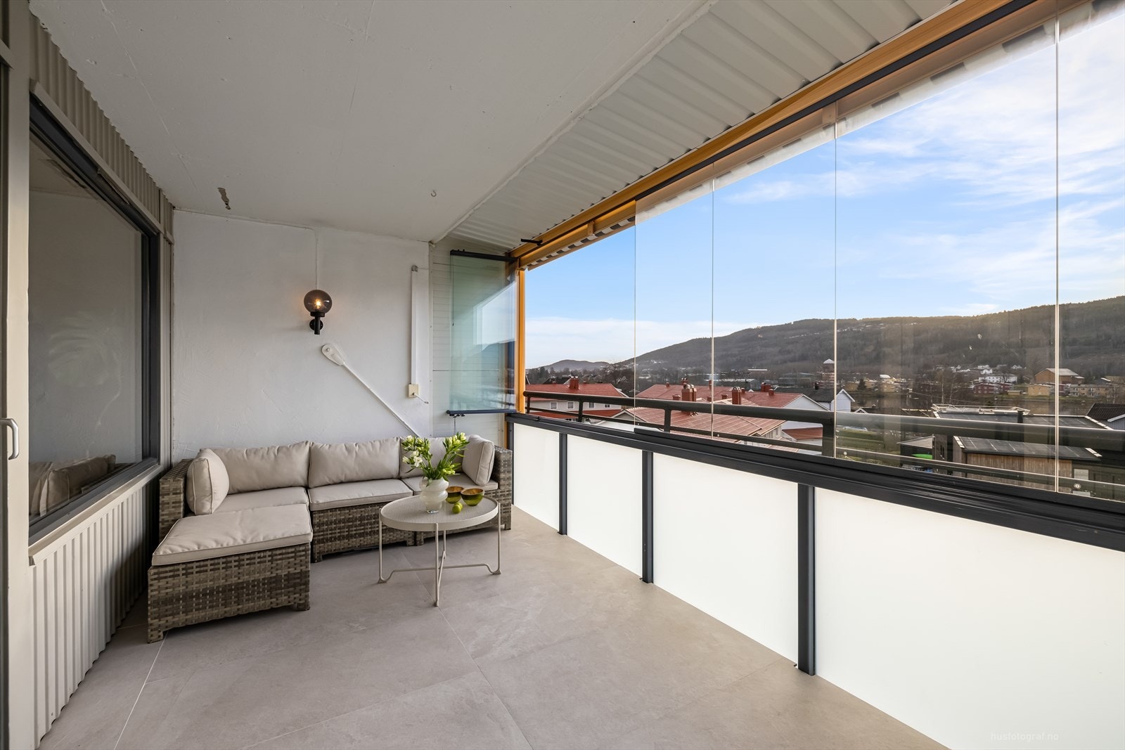 Flislagt balkong med plass til en koselig sofagruppe samt spisebord og gassgrill. Galleribilde
