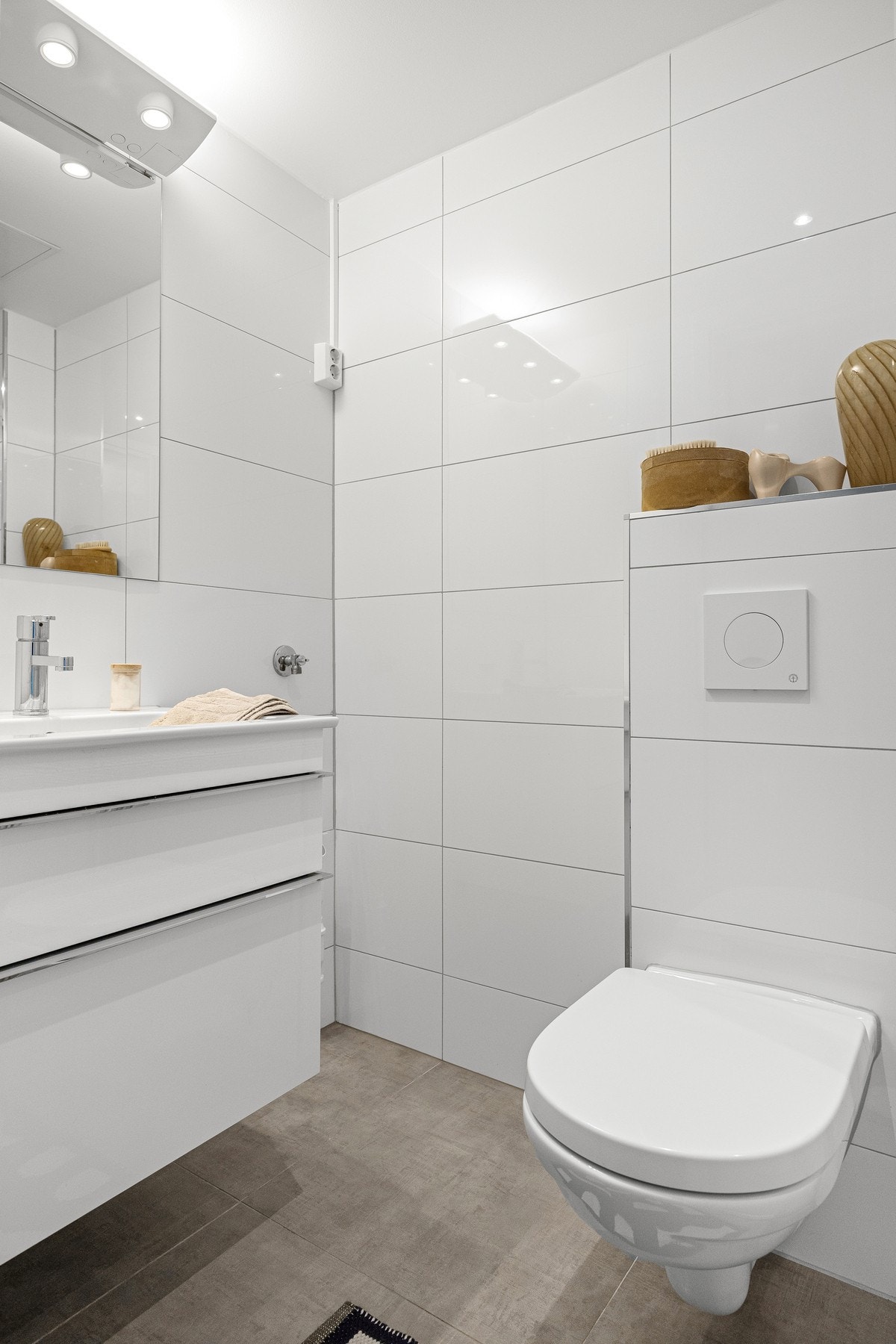 Badet inneholder dusjhjørne med skyvedør, servant med innredning, speilskap og vegghengt toalett. Opplegg og plass for vaskemaskin. Galleribilde