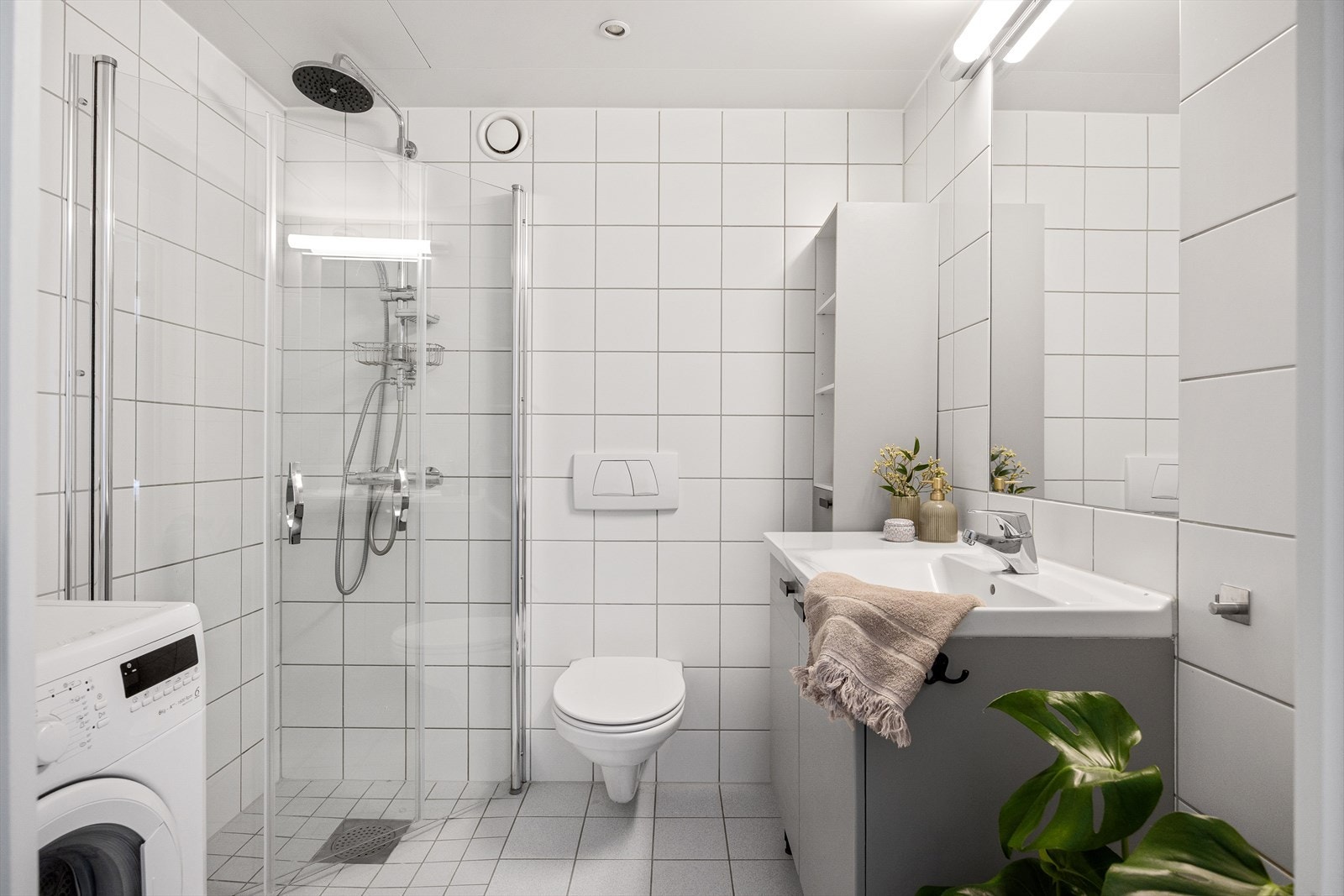 Det er montert et vegghengt toalett og dusjen er plassert i hjørnet med praktiske innfellbare dører. Galleribilde