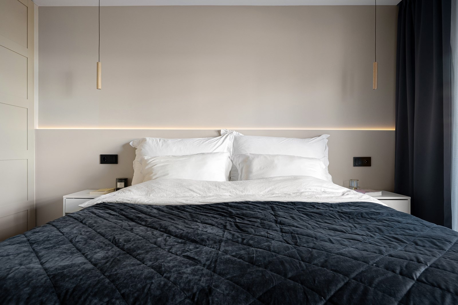 Gjennomtenkte løsninger med ledlys, praktisk plasserte stikkontakter og en midtplassert seng med tilhørende nattbord Galleribilde