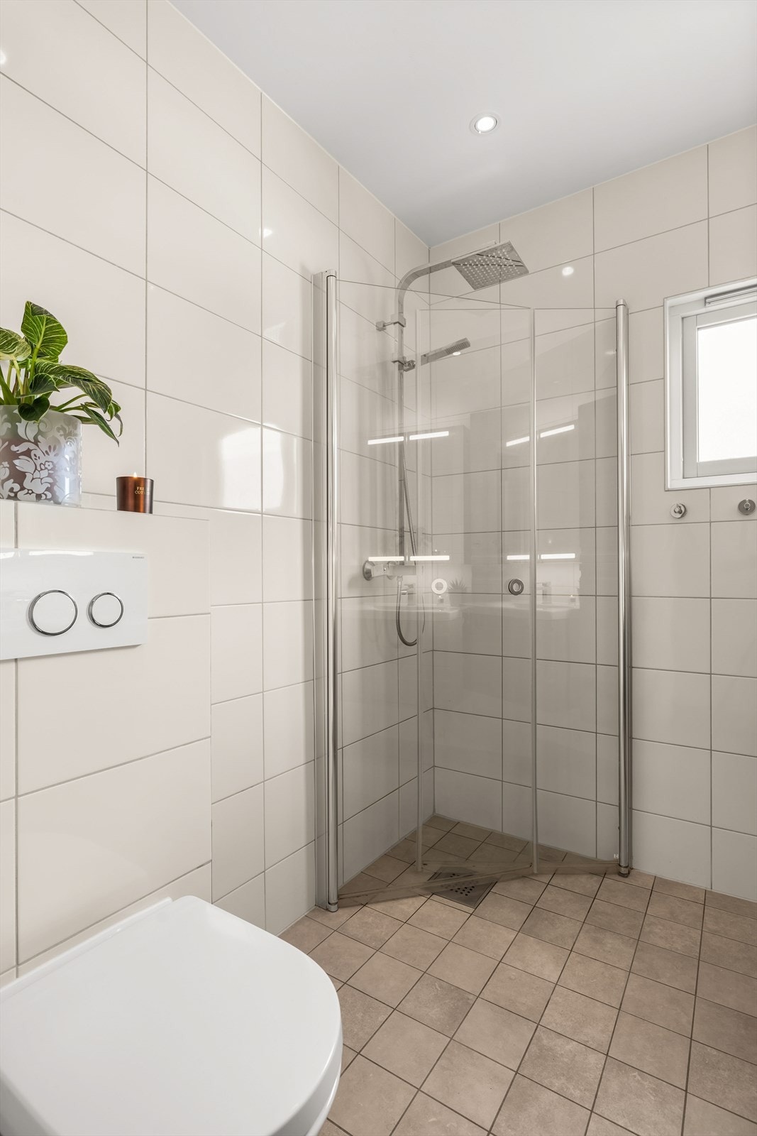 Badet er utstyrt med servant, høyskap, speilskap med belysning, veggmontert toalett og dusjvegger/hjørne. Galleribilde