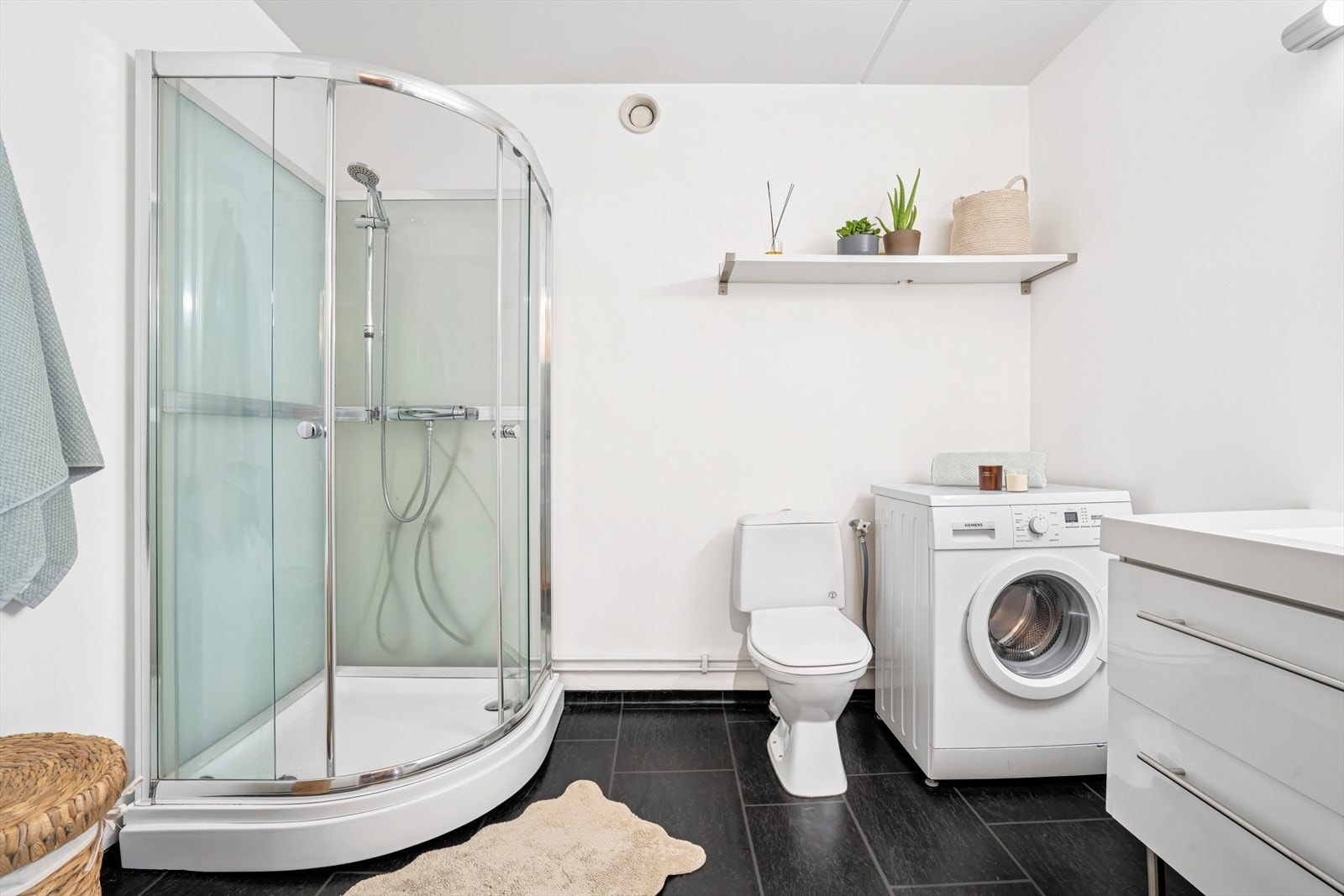 Innredning består av dusjkabinett, toalett, servant med underskap, speildel, lys og hylle. Det er opplegg og plass for vaskemaskin. Galleribilde