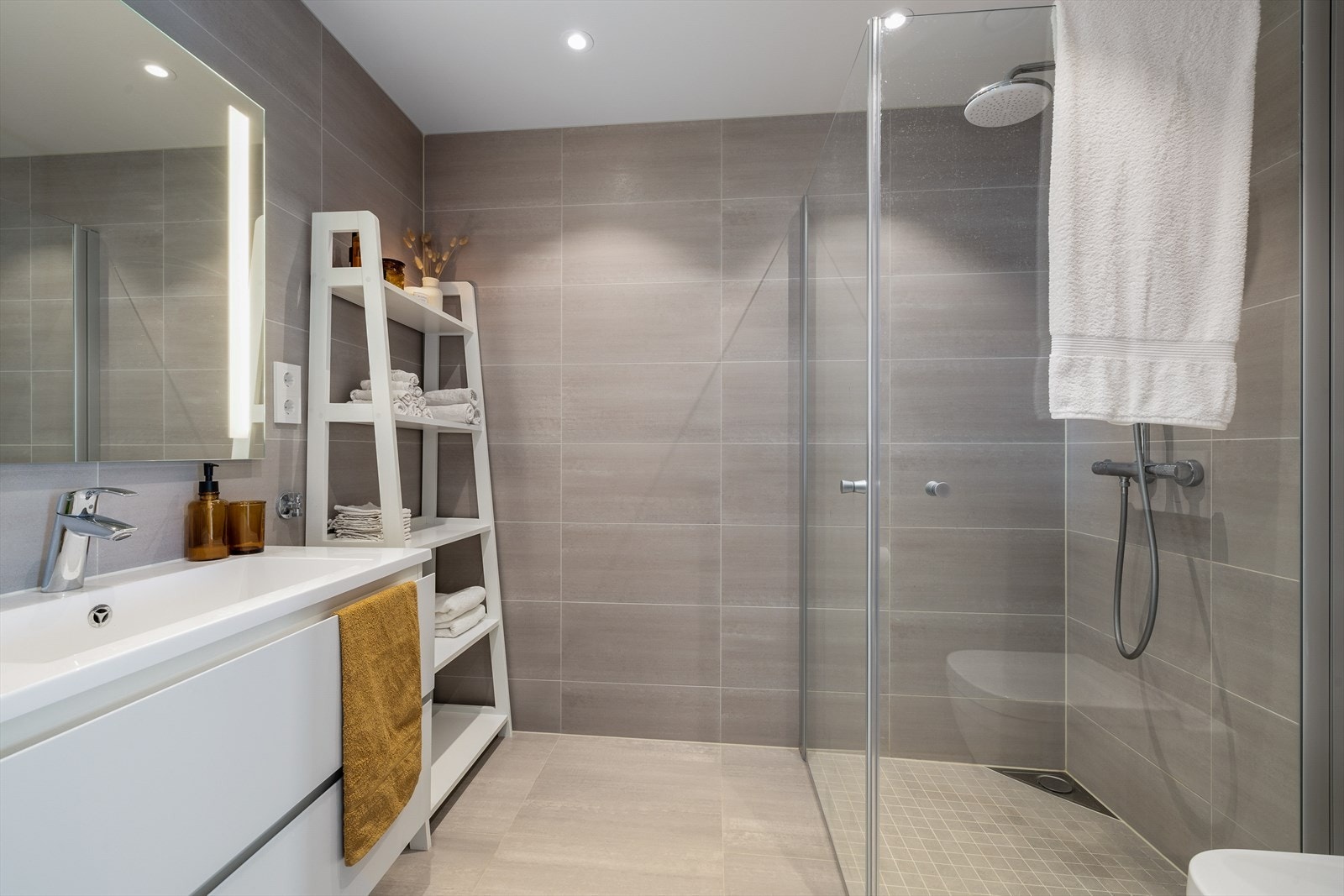 Det delikate, flislagte baderommet har en gjennomført stil med moderne innredning. Flisene på veggene og gulvet er nøye valgt for å skape en harmonisk og tidløs atmosfære. Galleribilde