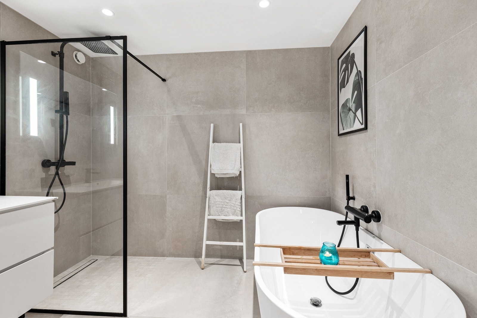 Badet er pent flislagt på gulv og vegger med elektrisk gulvvarme, med et moderne og stilrent uttrykk. Galleribilde