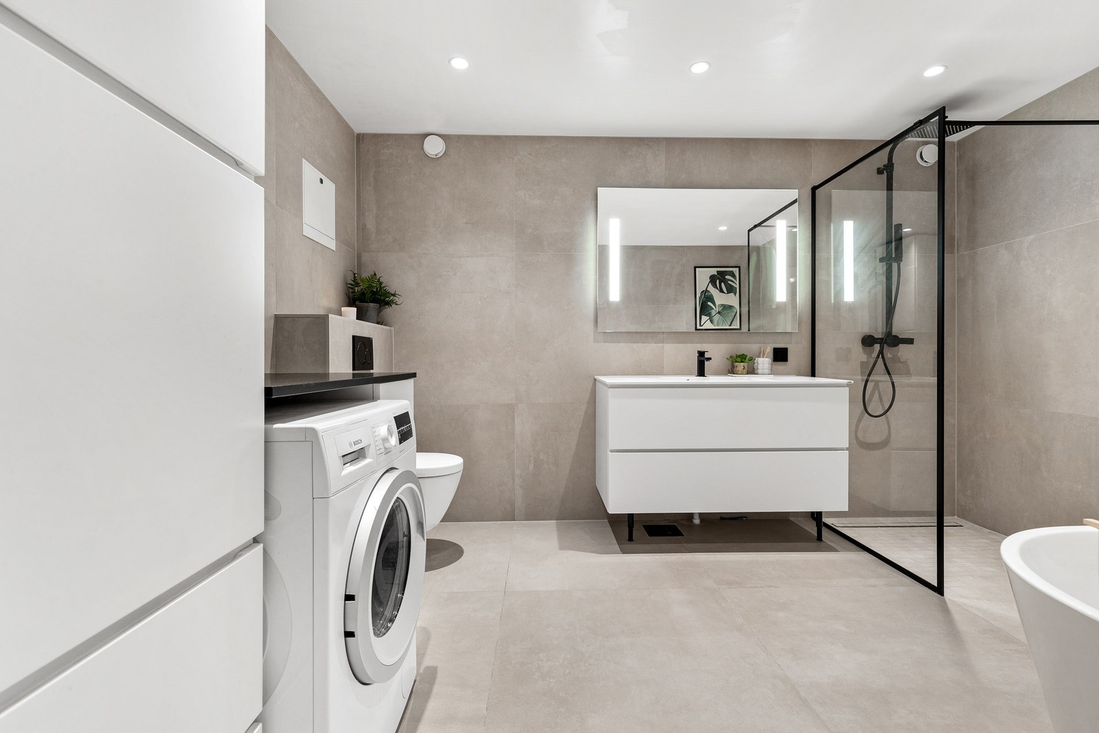 Badet har flere praktiske løsninger, blant annet opplegg og plass til vaskemaskin i tilpasset innredning. Galleribilde