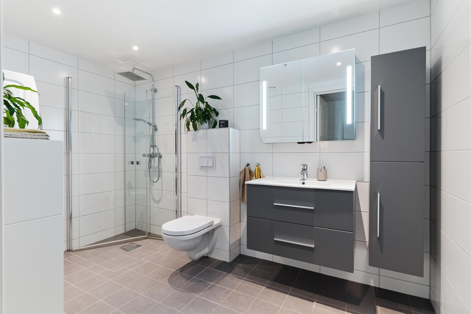 Ett innbydende bad som har har flislagte overflater på vegger og gulv. Badet har varmekabler i gulv og downlights i himling. Galleribilde