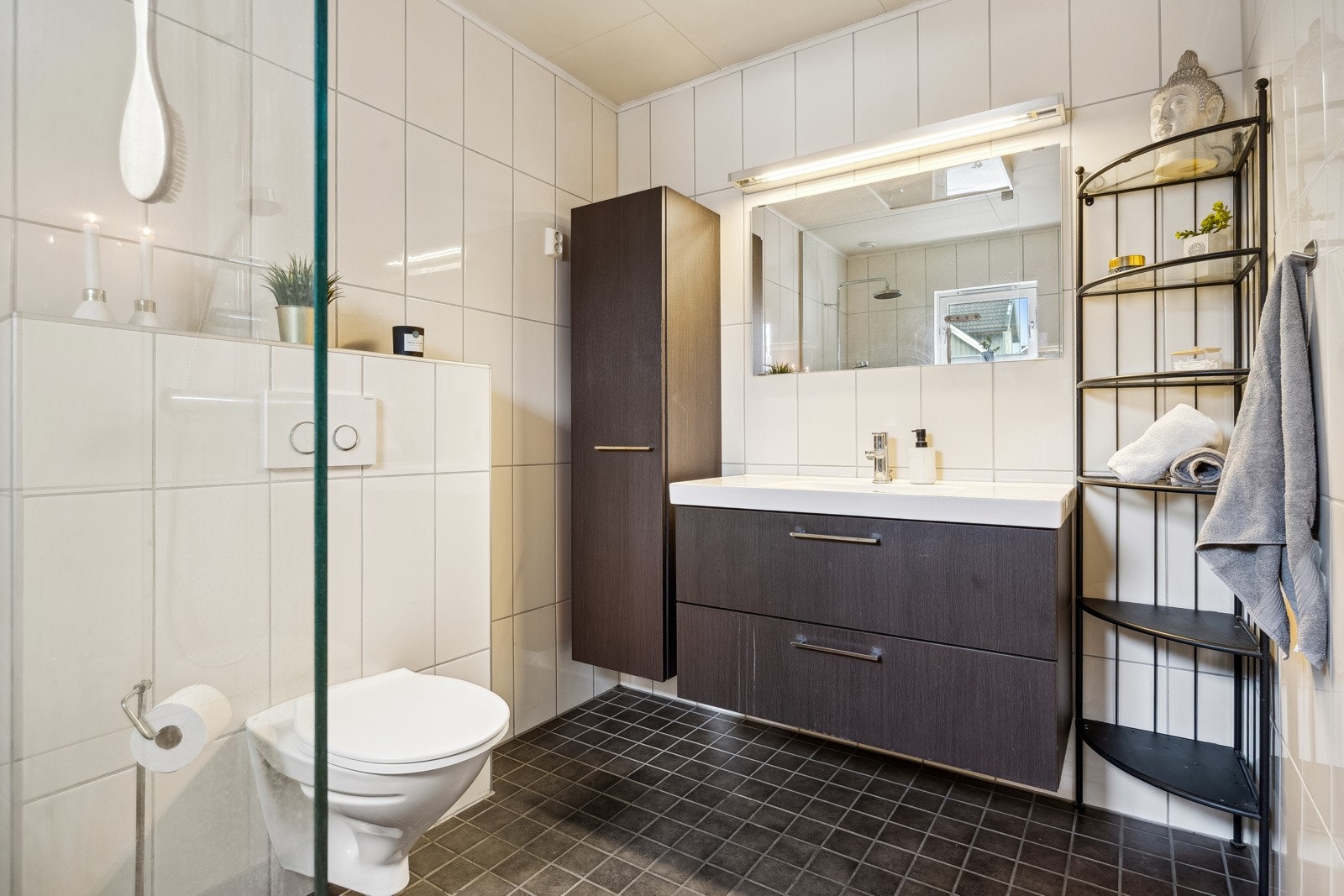 Flislagt baderom utstyrt med servantinnredning, speil med overlys, skap, dusjnisje og toalett. Galleribilde