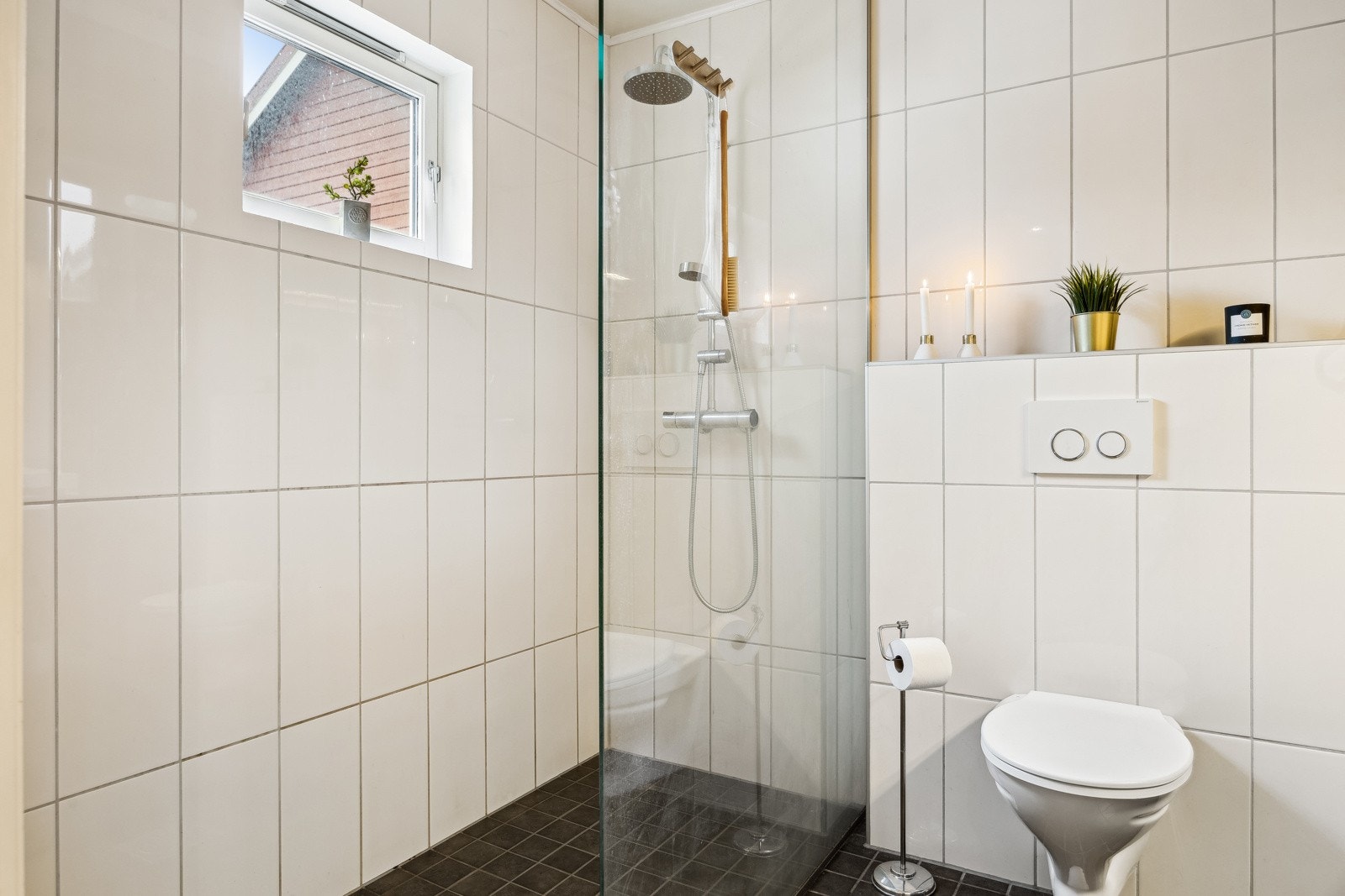 Dusjnisjen er utstyrt med en glassvegg og et vegghengt dusjarmatur som har både hånddusj og regndusj. Galleribilde