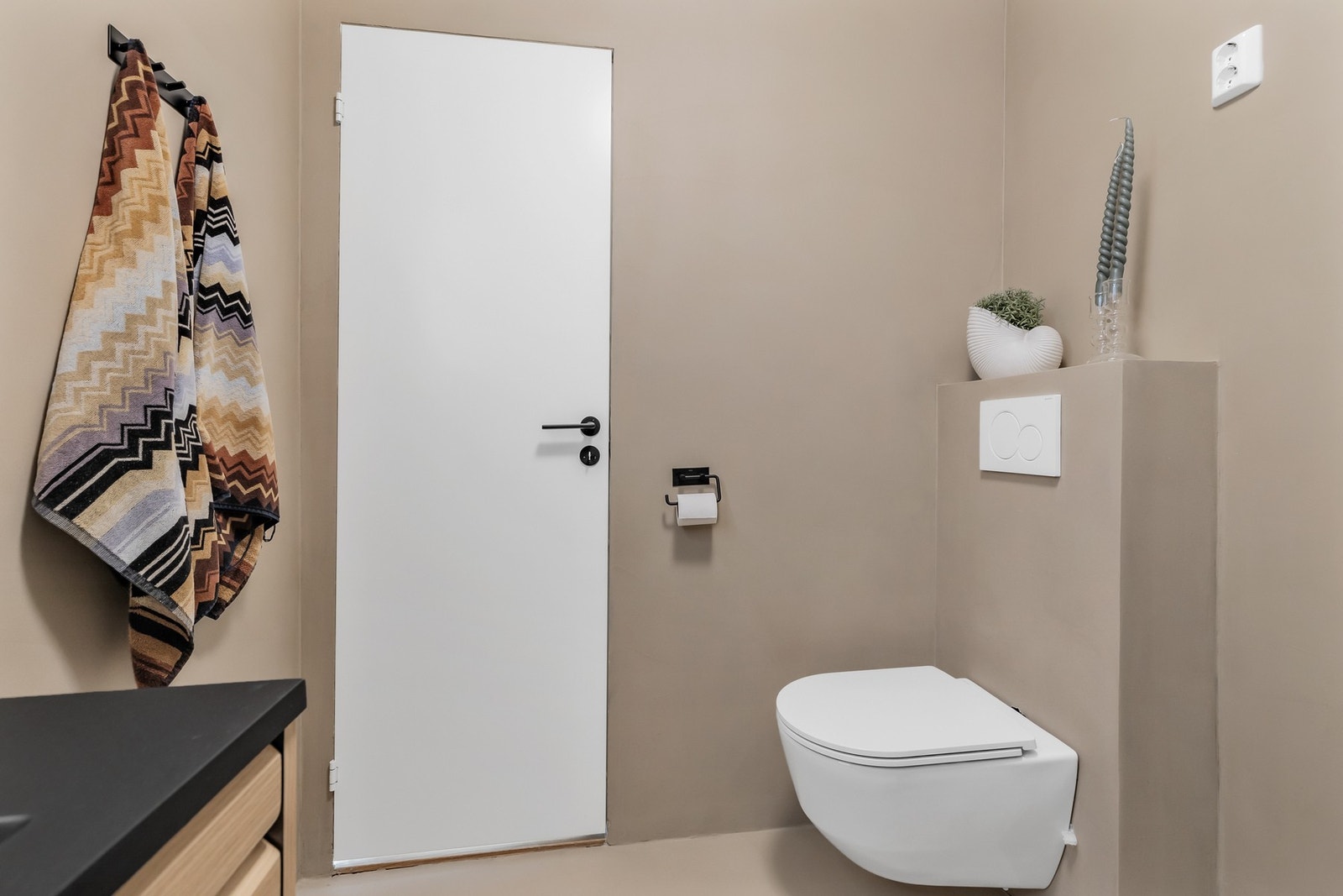 Badet er utstyrt med vegghengt toalett, dusjhjørne med innfellbare dører og innredning med ovenpåliggende servant Galleribilde