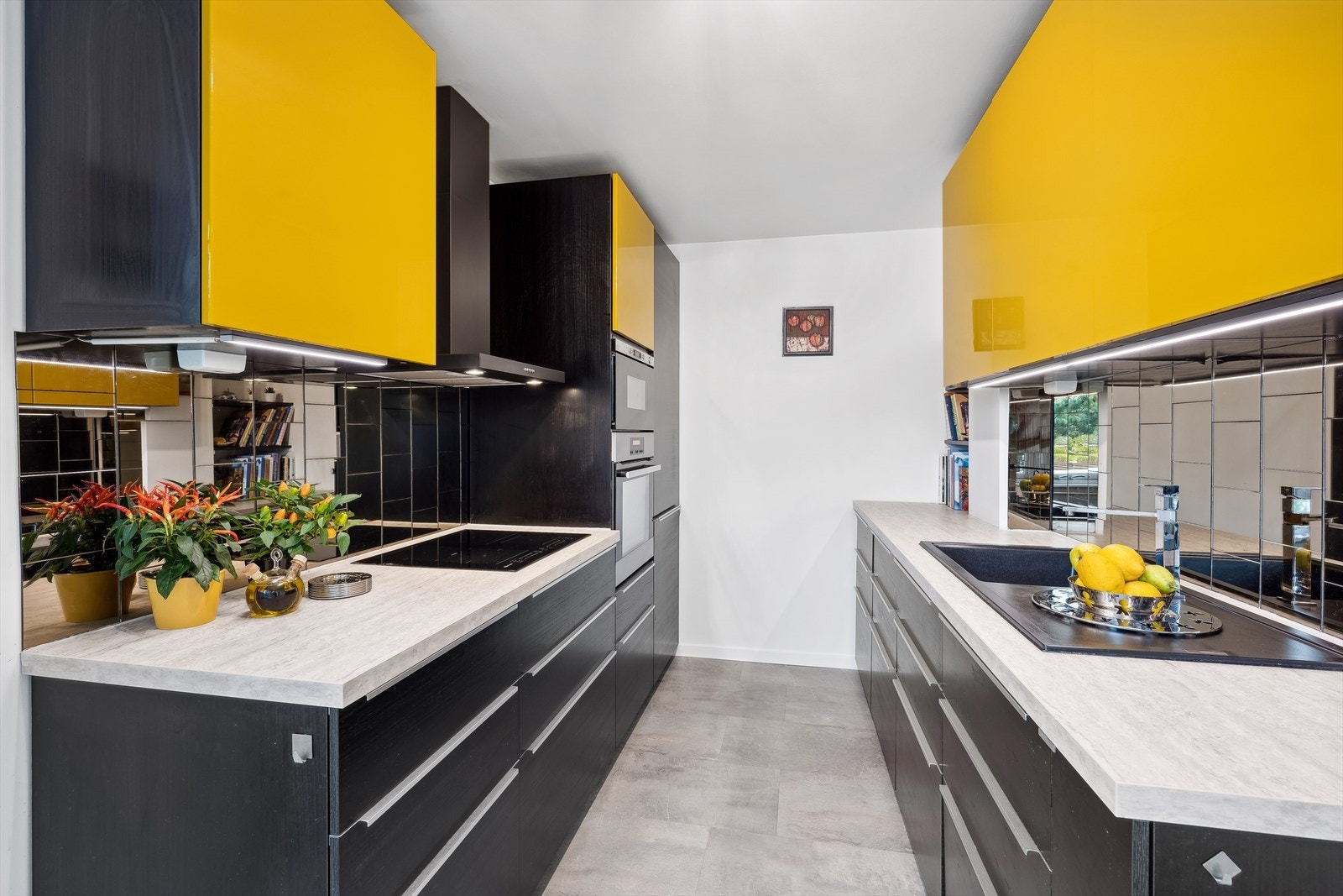 Kjøkkenets innredning fra 2017 har glatte fronter, laminat benkeplate med nedfelt oppvaskkum, fliser over benk, belysning under overskap og ventilator Galleribilde