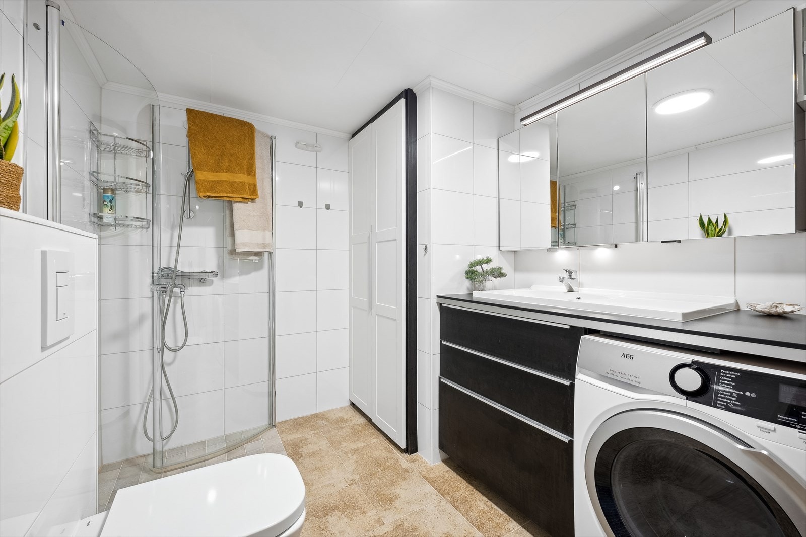 Et av badene i 1. etasje er fra 2015. Rommet har en god størrelse og er pent innredet. Det er opplegg for vaskemaskin og tørketrommel. Rommet fungerer som et kombinert bad/vaskerom. Det er varmekabler i gulvet. Galleribilde