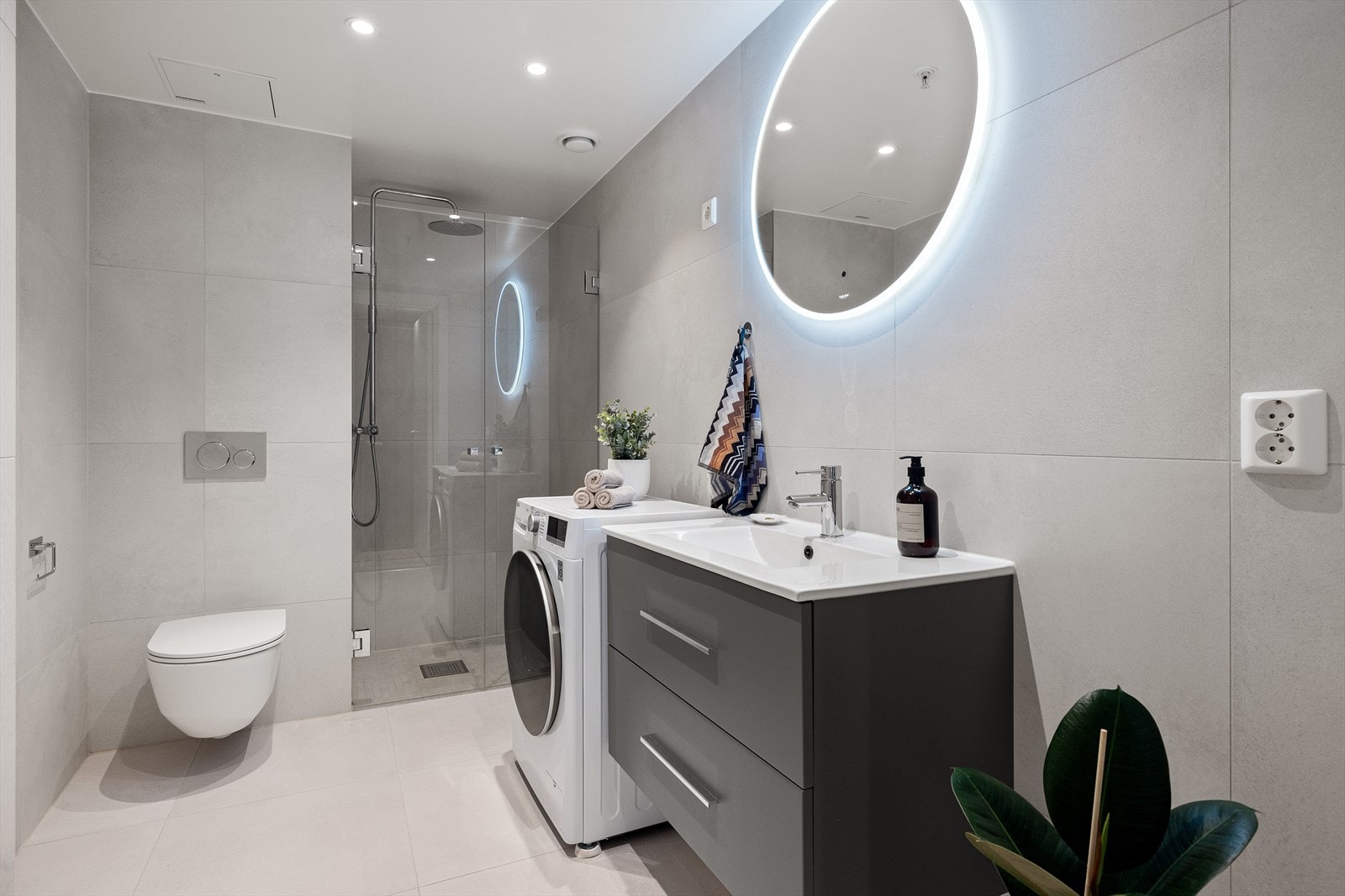 Stort, stilrent og delikat baderom med dusjnisje, vegghengt toalett og gulvvarme. Opplegg for vaskemaskin og tørketrommel Galleribilde