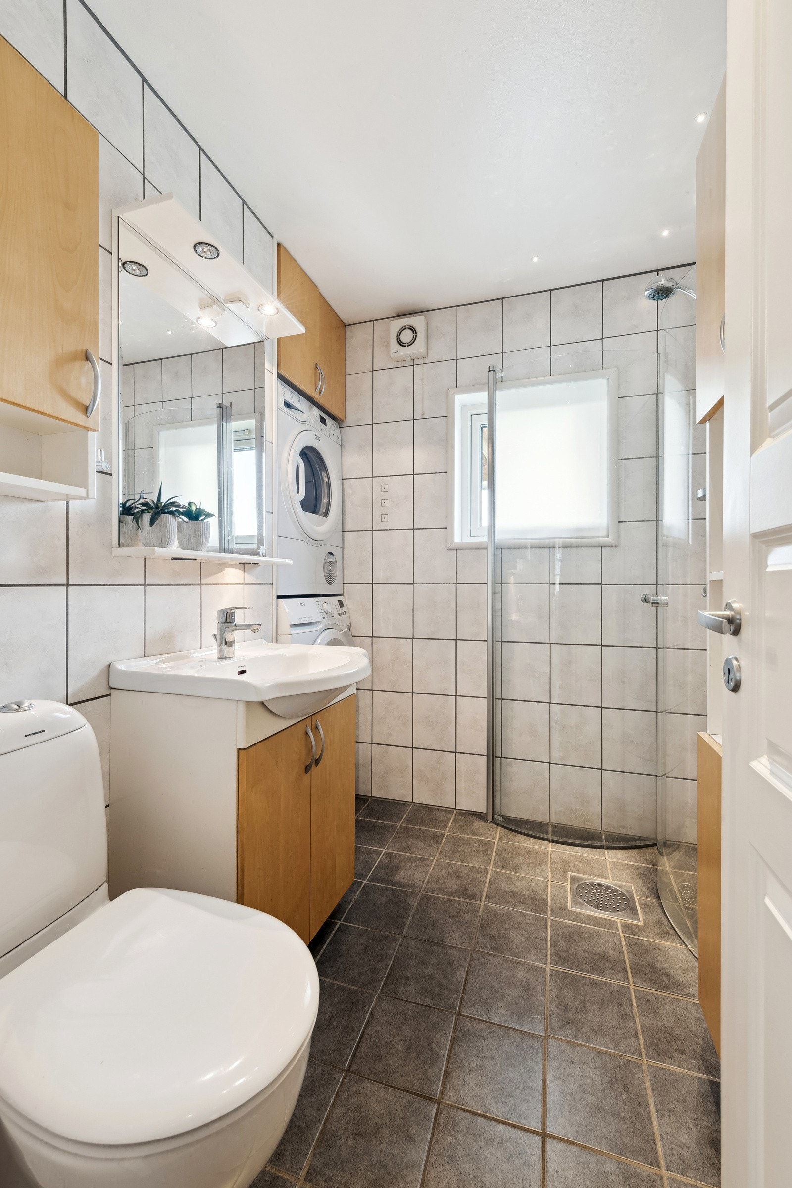 Baderomsinnredningen består av servantskap med ovenpåliggende servant, speil, hylle og belysning på vegg. Dusj på gulv med innfellbare dører av glass Galleribilde