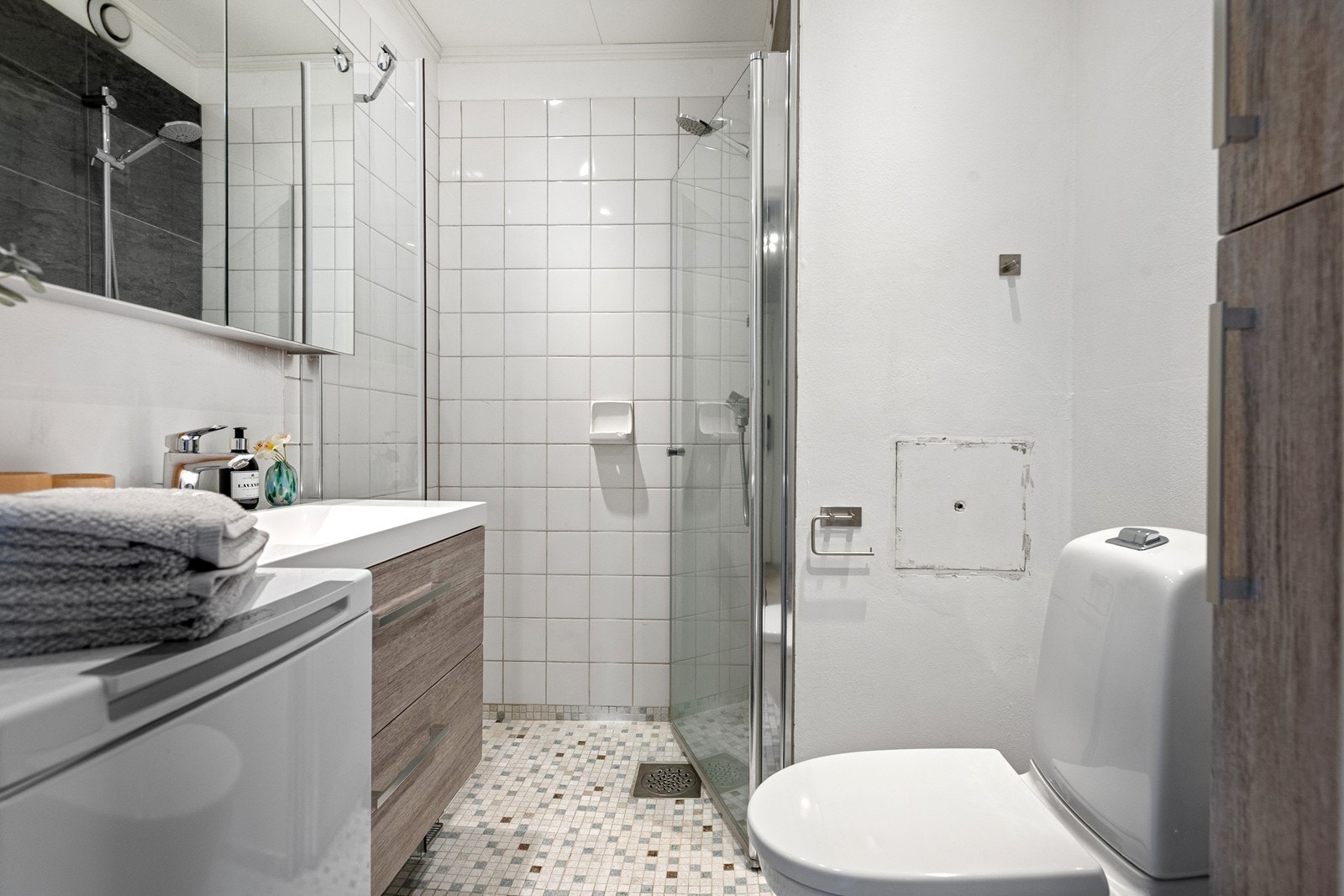 Stilrent og flislagt bad med gulvvarme, dusjhjørne, innfellbare dusjdører, wc og opplegg for vaskemaskin Galleribilde