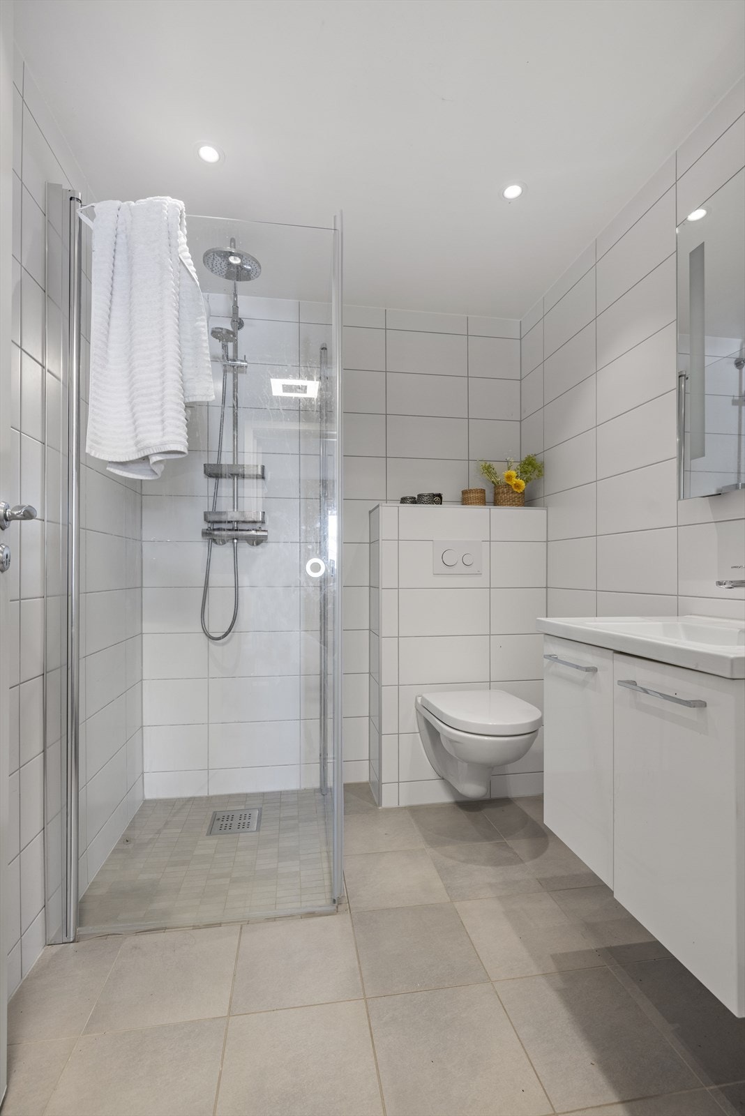Flislagt bad/wc fra 2017 med varmekabler i gulv. Badet er innredet med servant med underskap, vegghengt toalett og dusjhjørne/dører i glass. Plastsluk med vannlås Galleribilde