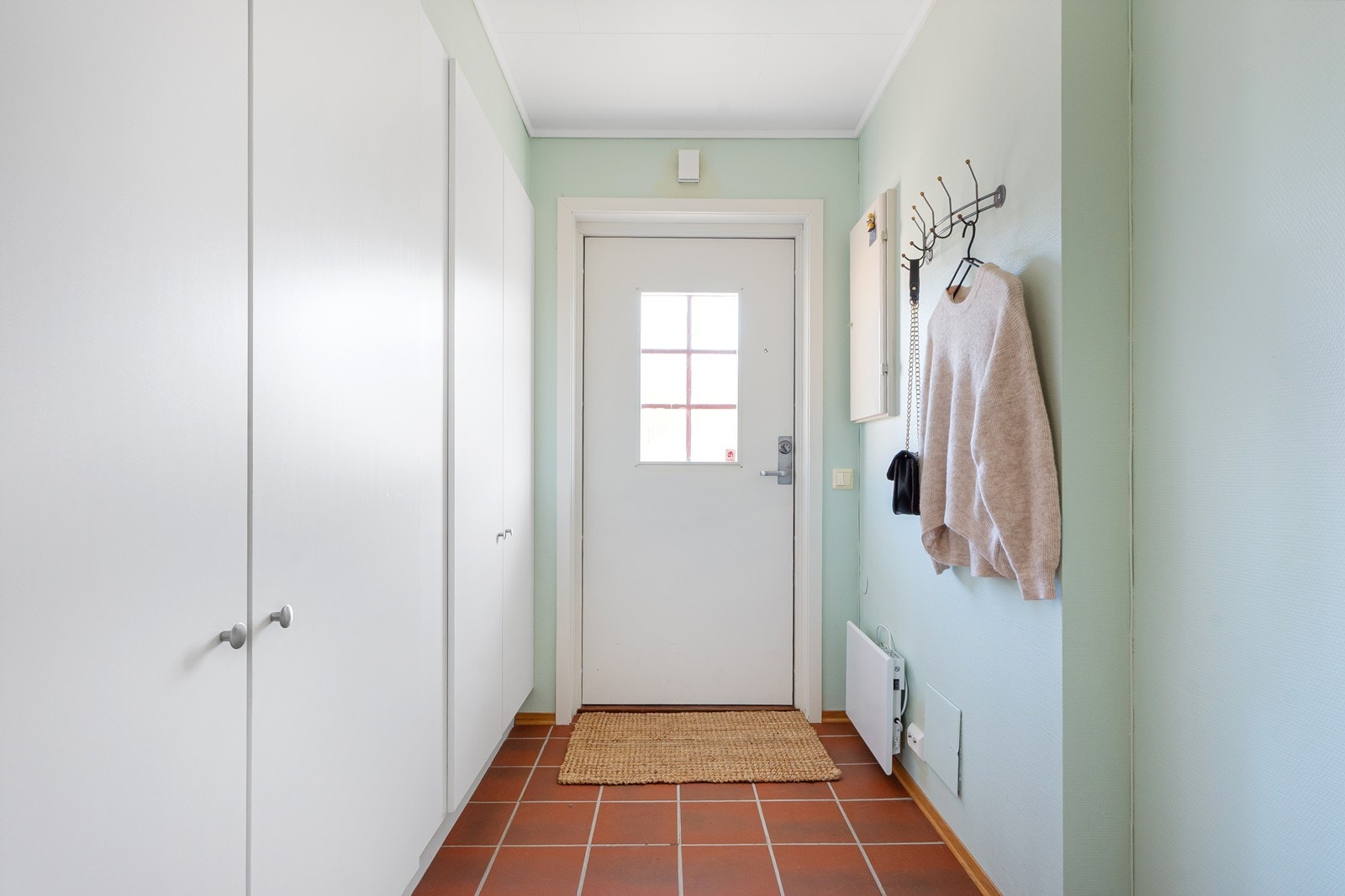 Velkommen inn ønskes i en flislagt gang med god oppbevaringsplass i garderobeskap og knaggrekke. Galleribilde