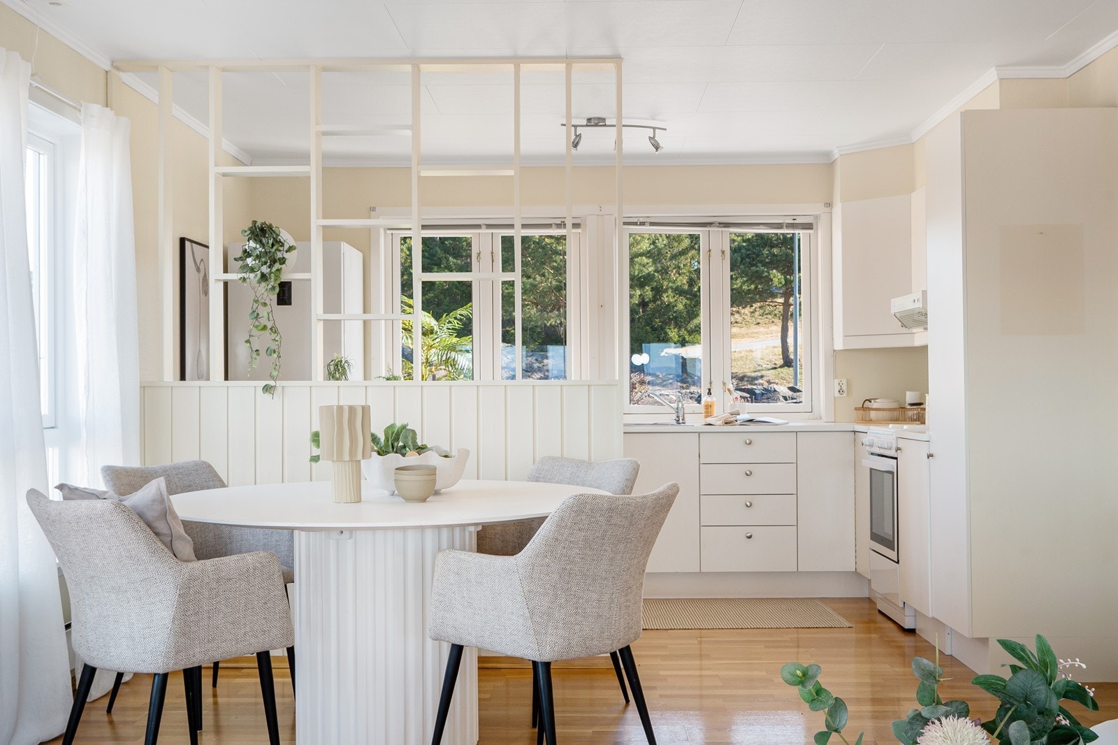 Kjøkkenet ligger i åpen løsning mot stuen med spisestue, delt av en lettvegg med åpne hyller som gir et naturlig skille mellom sonene. Galleribilde