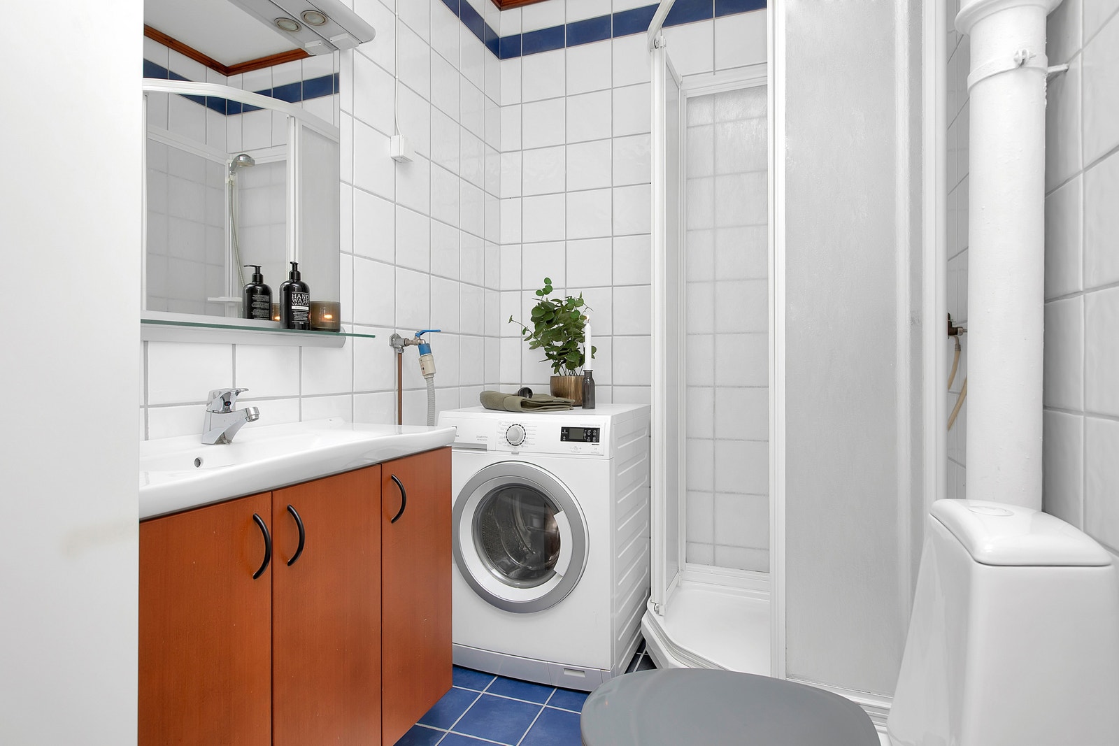 Helfliset bad utstyrt med dusjkabinett, WC, servant i innredning og vaskemaskin Galleribilde