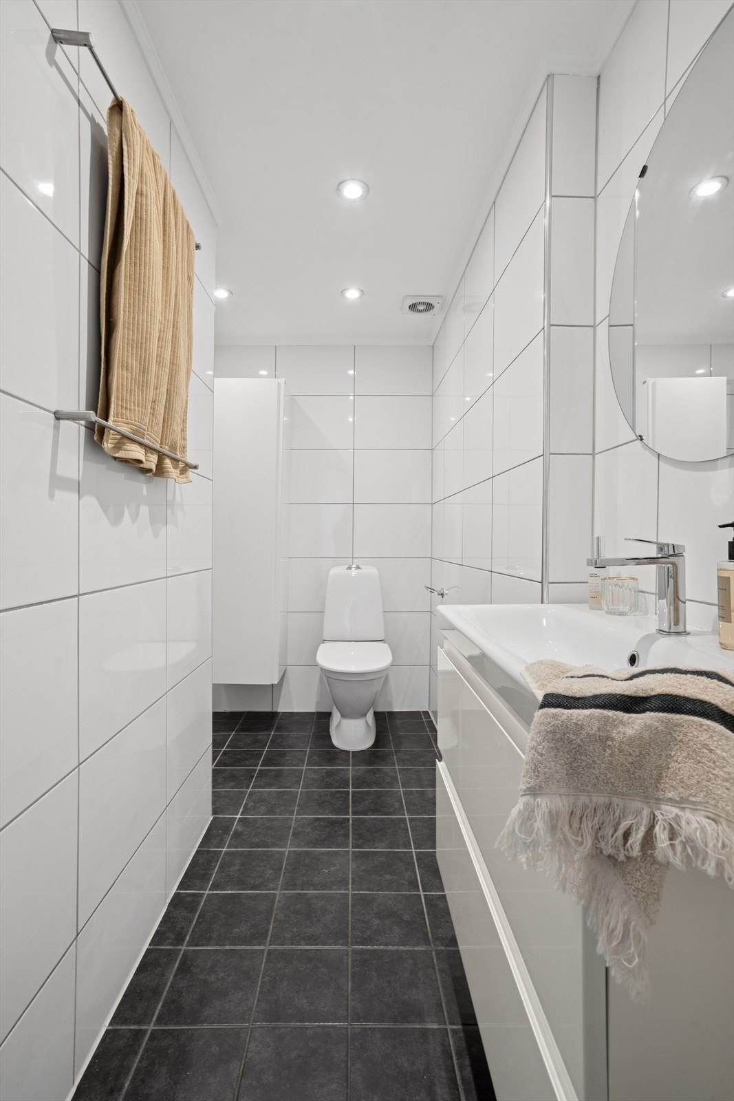 Pent flislagt bad med store fliser og downlights i himling. Galleribilde