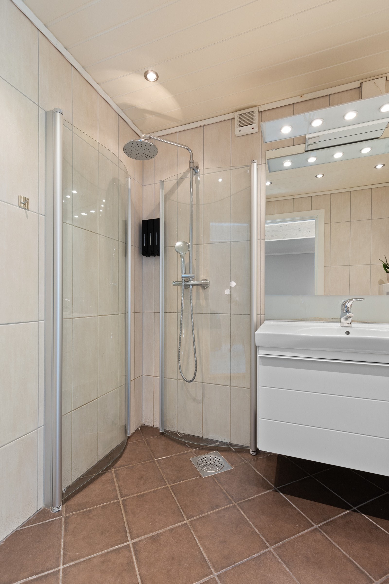 Videre har badet et vegghengt toalett og separat dusjhjørne med innfellbare glassdører og regnfallsdusj. Det er lagt varmekabler i gulv og himlingen er lyssatt med downlights. Galleribilde