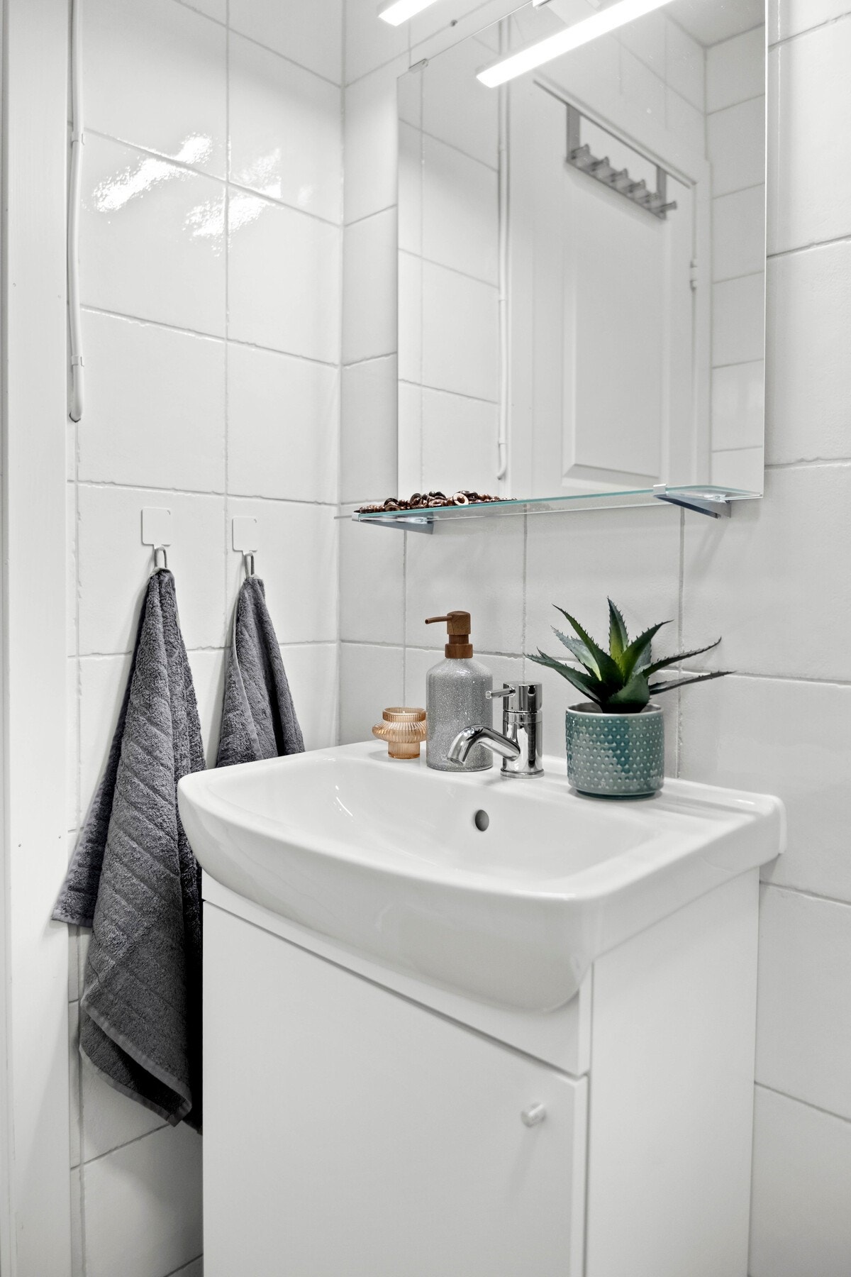 adet har vegghengt servantinnredning med dører og ovenpåliggende servant, samt speil med overlys. Galleribilde