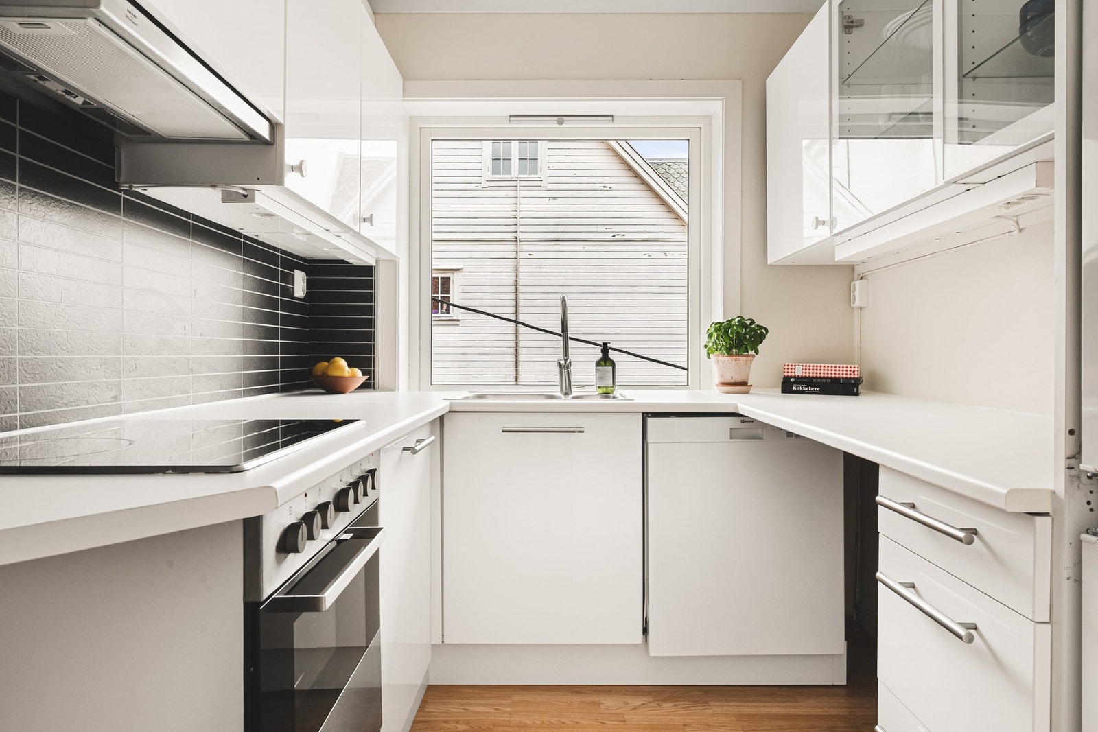 Kjøkkeninnredning består av slette hvite fronter, to glasskap og laminat benkeplate med nedfelt vask av stål. Galleribilde