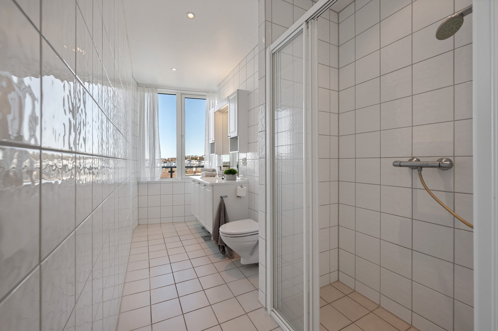 Badet har vegghengt toalett og dusjnisje med herdede glassdører Galleribilde