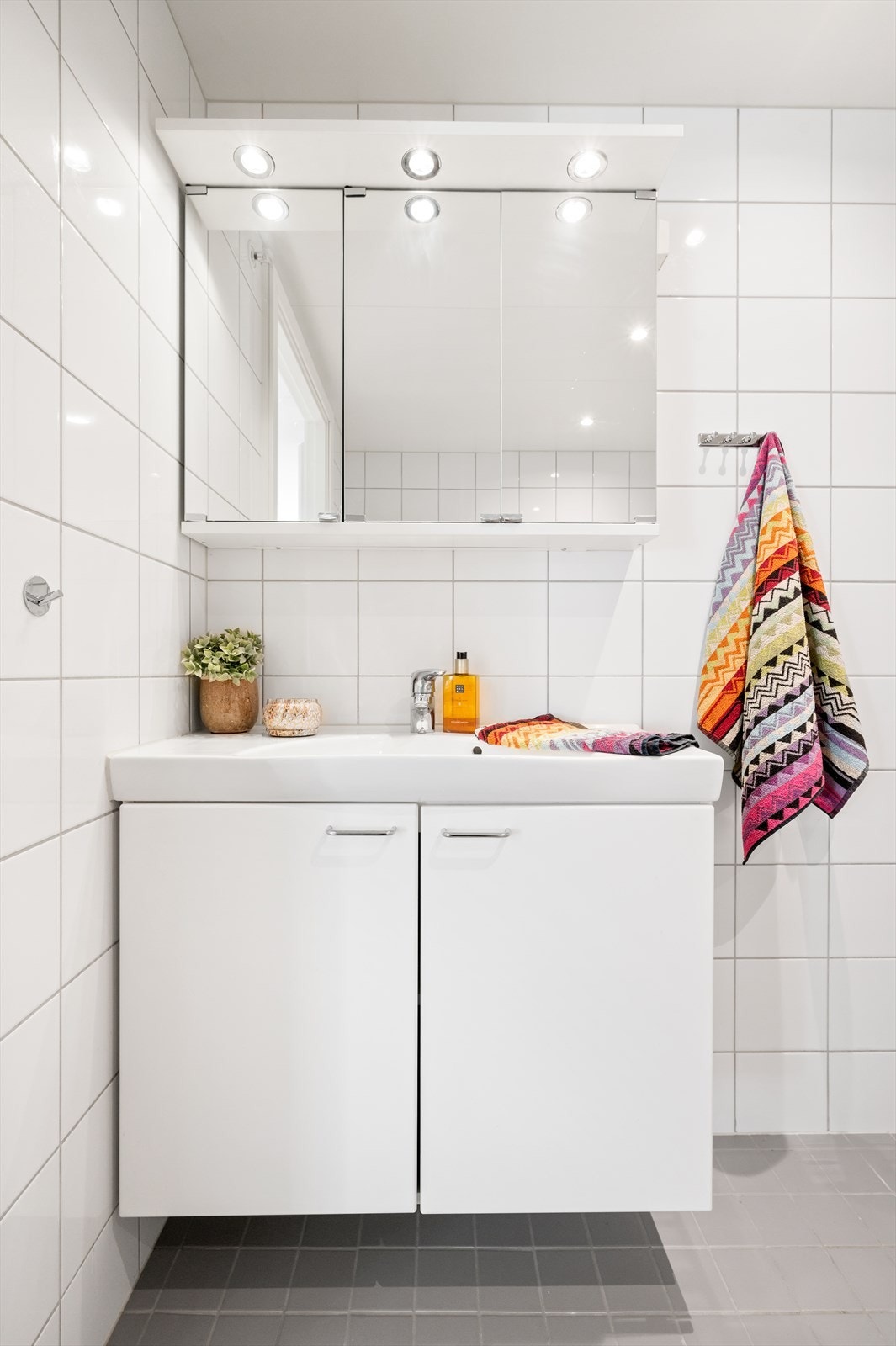 Videre har badet en lekker innredning med en heldekkende servant på et hvitt servantskap og et speilskap med overlys. Galleribilde