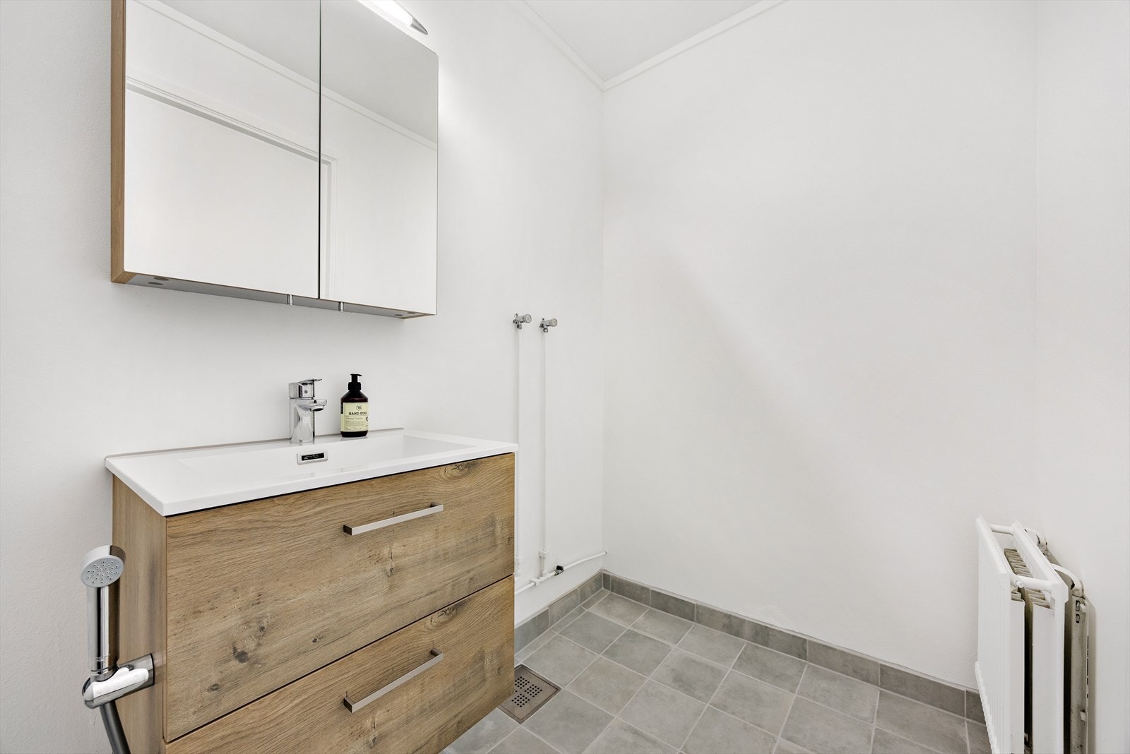 Toalettrommet inneholder servantseksjon med skuffer, overskap med speilfronter og gulvmontert klosett. Galleribilde