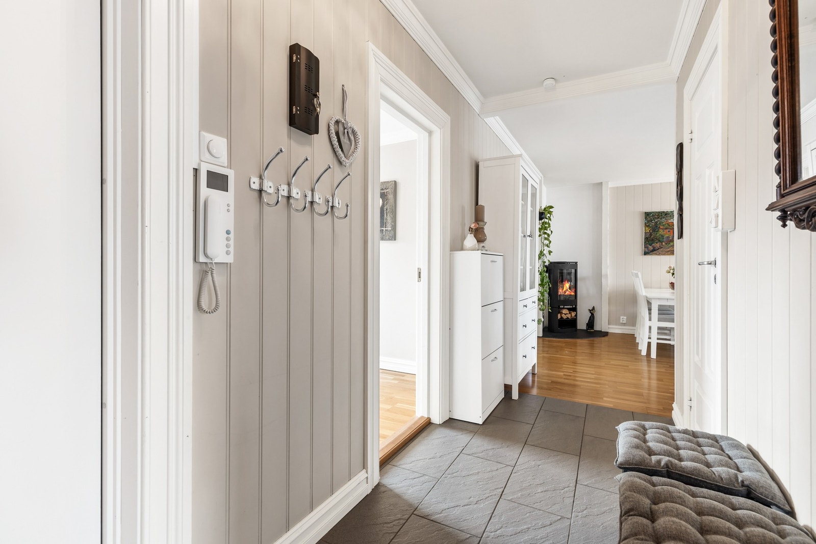 Romslig entré med fliser på gulv, panel på vegger og slett flate i himling Galleribilde