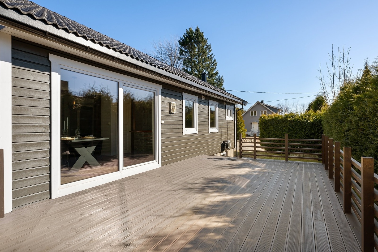 Romslig veranda med gode solforhold og god plass til utemøblement. Enkel tilgang til hagen via trappen. Galleribilde