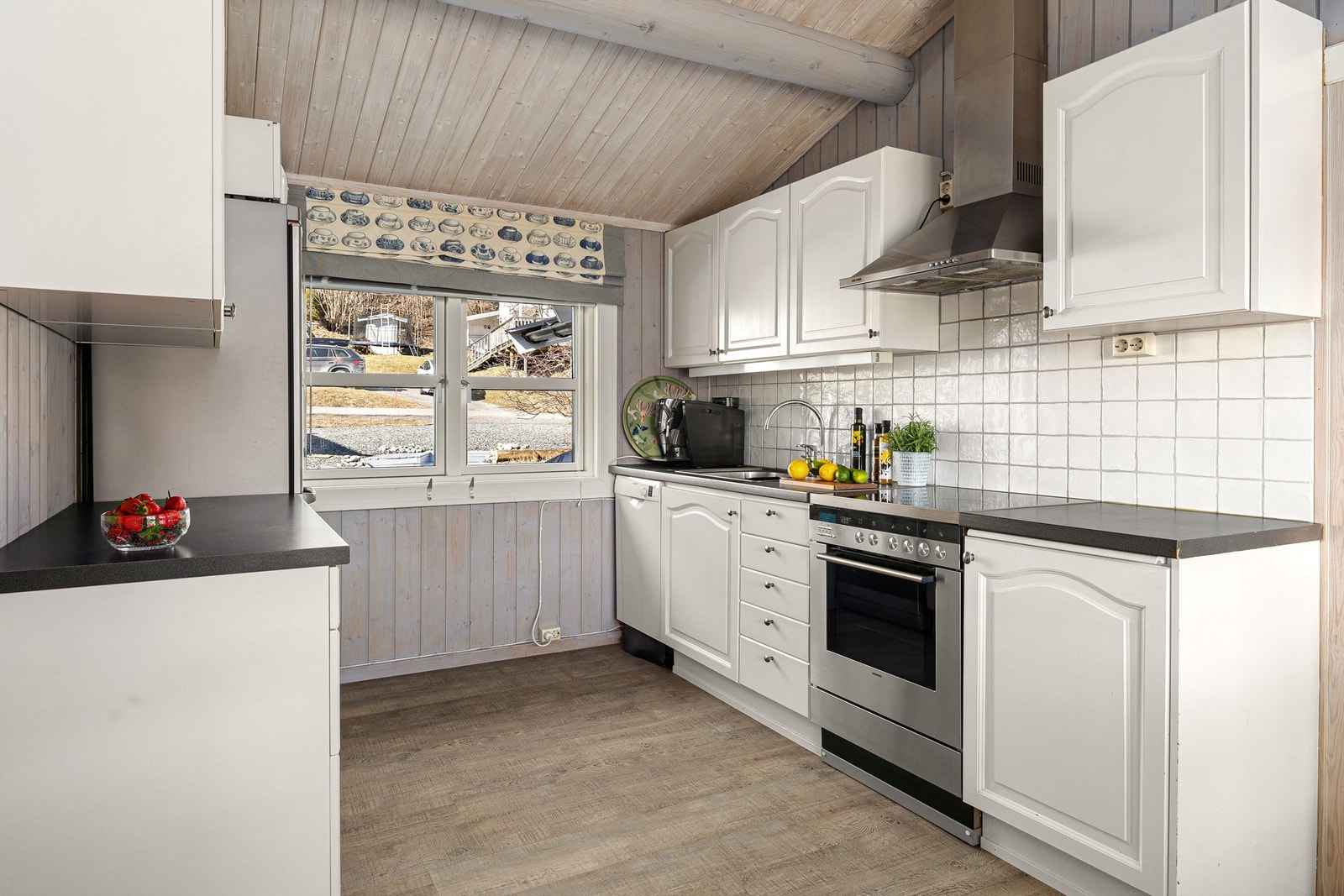 Kjøkkeninnredning med malt innredning og flis mellom benk og overskap. Galleribilde