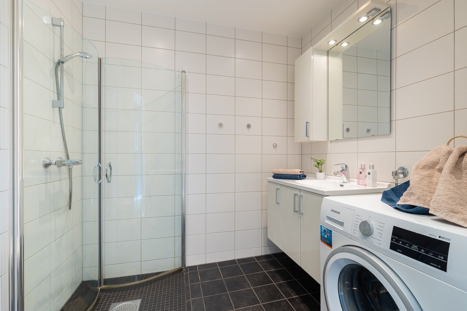 Boligens andre baderom er lyst og flislagt. Opplegg for vaskemaskin og tørketrommel. Galleribilde