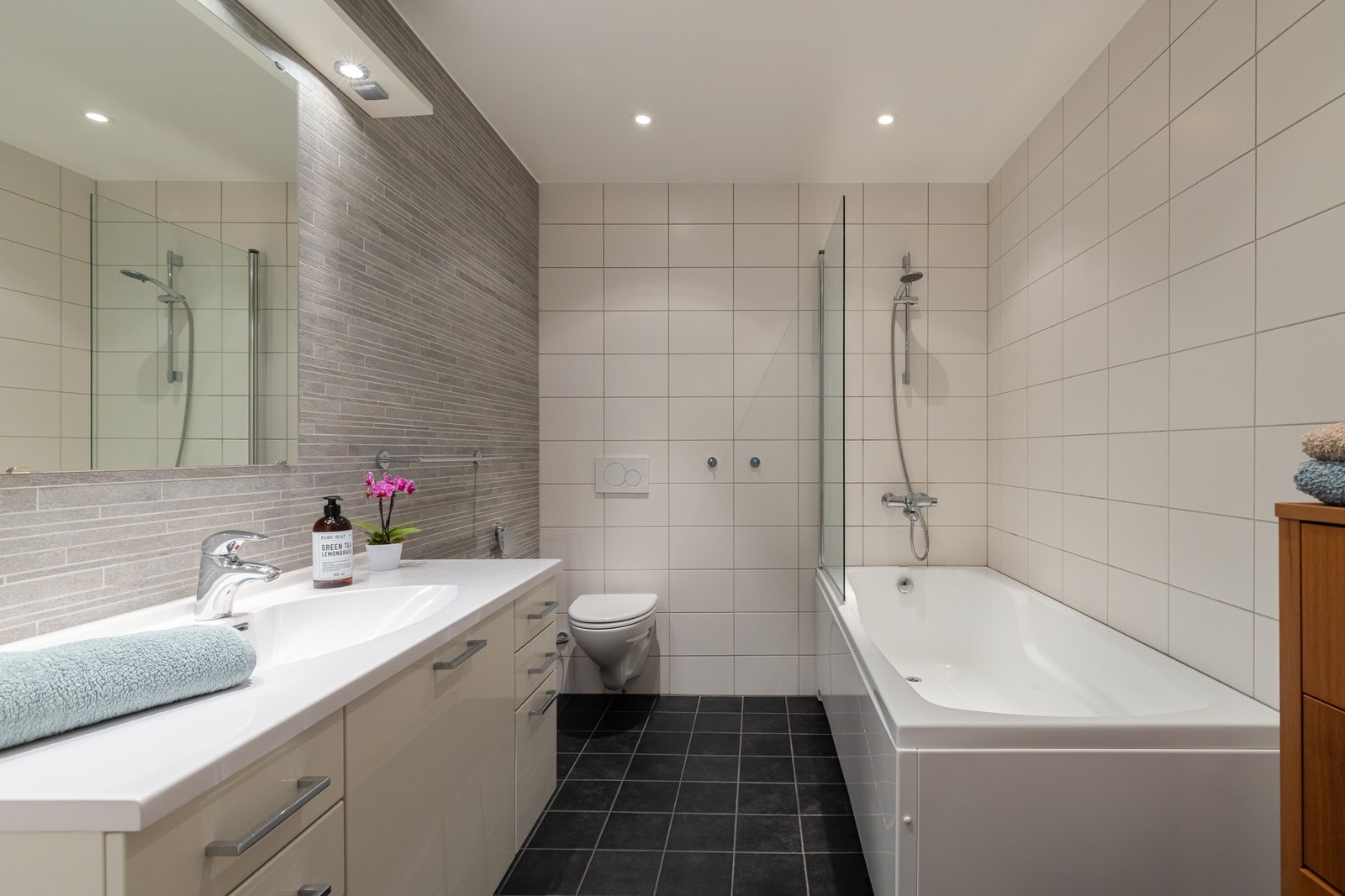 Innredningen består av servant på underskap/skuffer og speil. Videre er det vegghengt toalett og badekar med hånddusj. Galleribilde