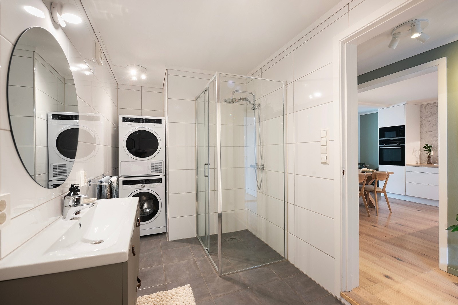 Badet i leiligheten er flislagt med varmekabler i gulvet, og det er plass til vaskemaskin og tørketrommel i tilbaketrukket krok Galleribilde