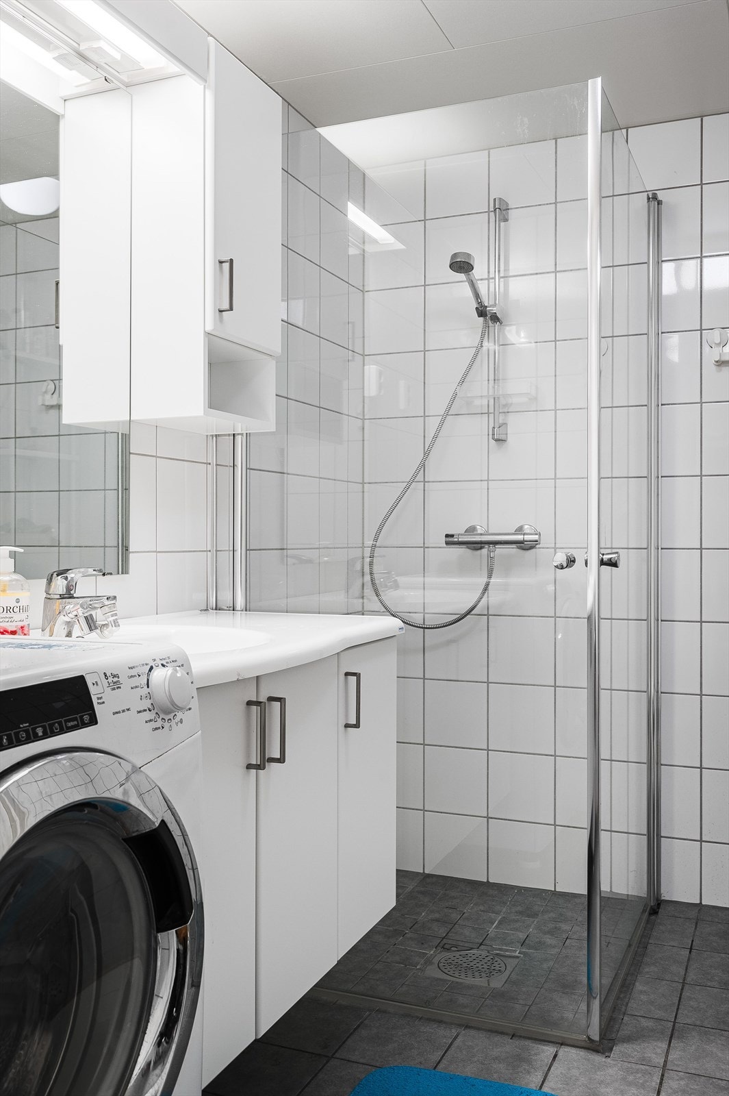 Baderommet er utstyrt med baderomsinnredning med servant, speil med belysning, dusjhjørne med innfellbare glassdører og toalett. Det er også plass og opplegg for vaskemaskin. Galleribilde