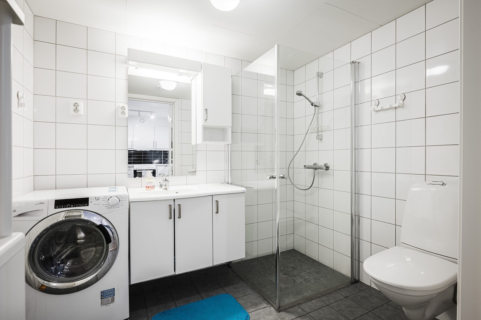 Leiligheten har et lyst og moderne flislagt baderom fra byggeåret 2015. Baderommet har mørke fliser på gulv med vannbåren gulvvarme, hvite fliser på veggene og balansert ventilasjon. Galleribilde