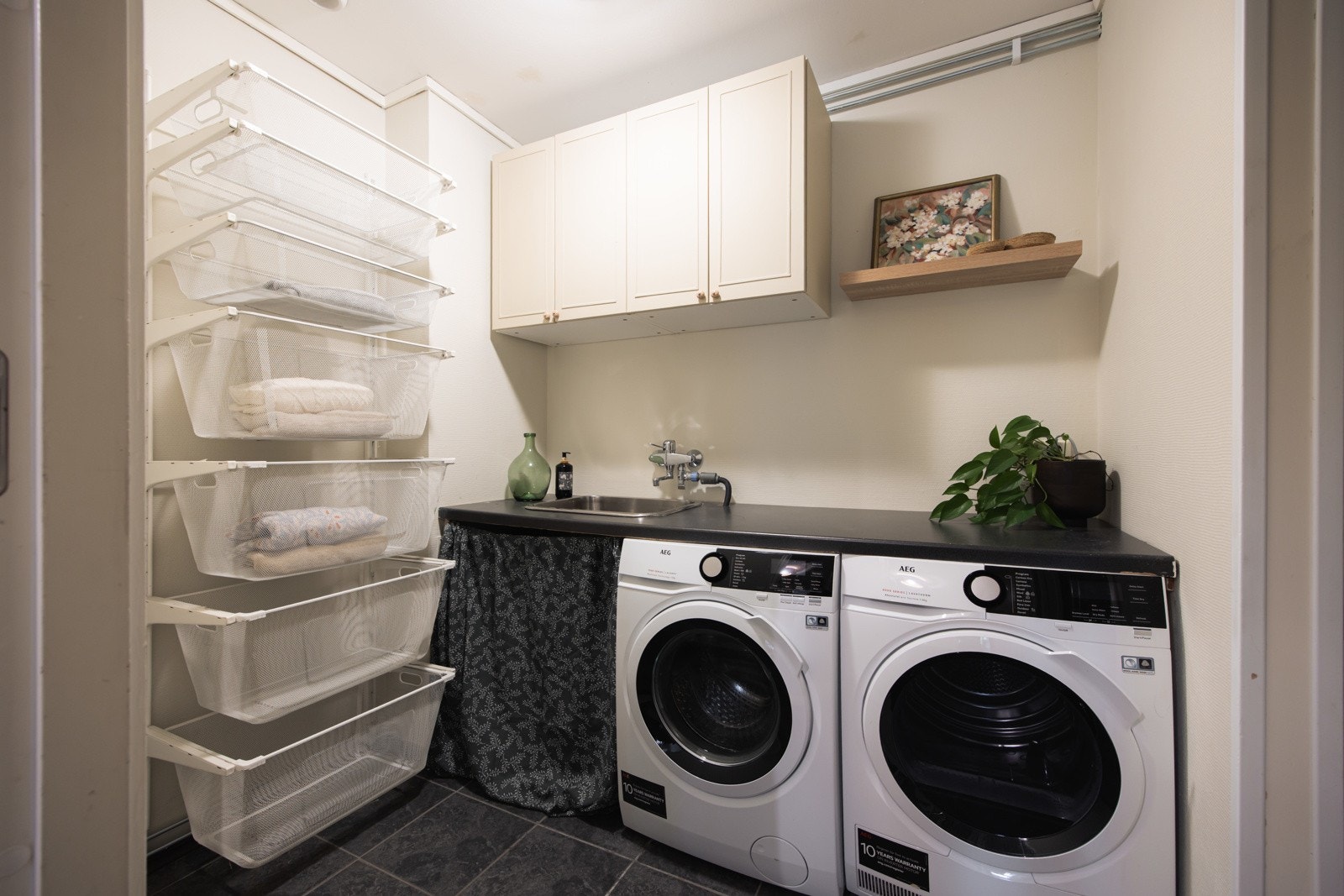 Rommet er innredet med overskap på vegg, benkeplate med nedfelt skyllekum og opplegg for vaskemaskin - en smart løsning for en enklere hverdag. Galleribilde