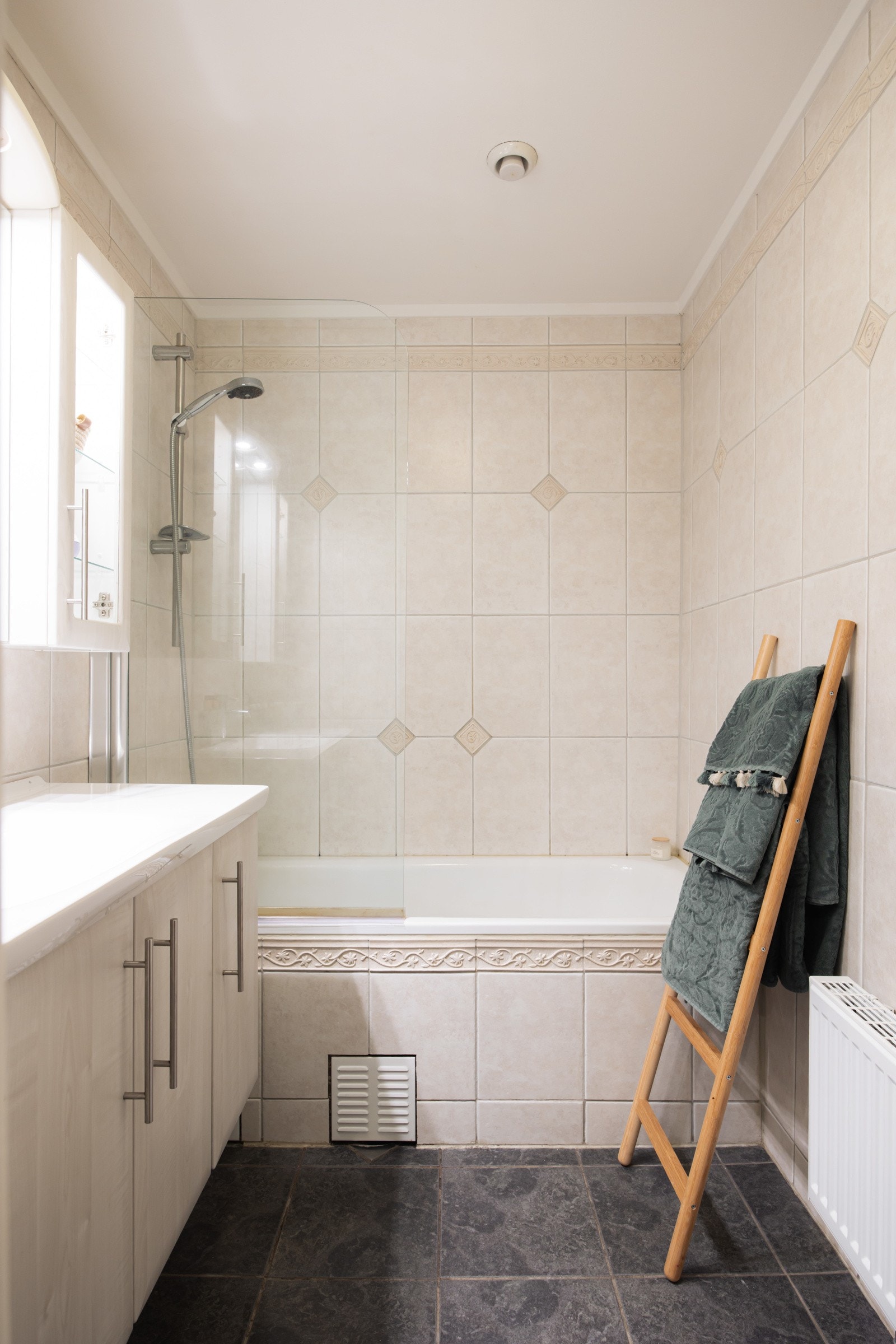 Badet er innredet med servantinnredning, speil på vegg over servant og innmurt badekar med glassdør. Galleribilde