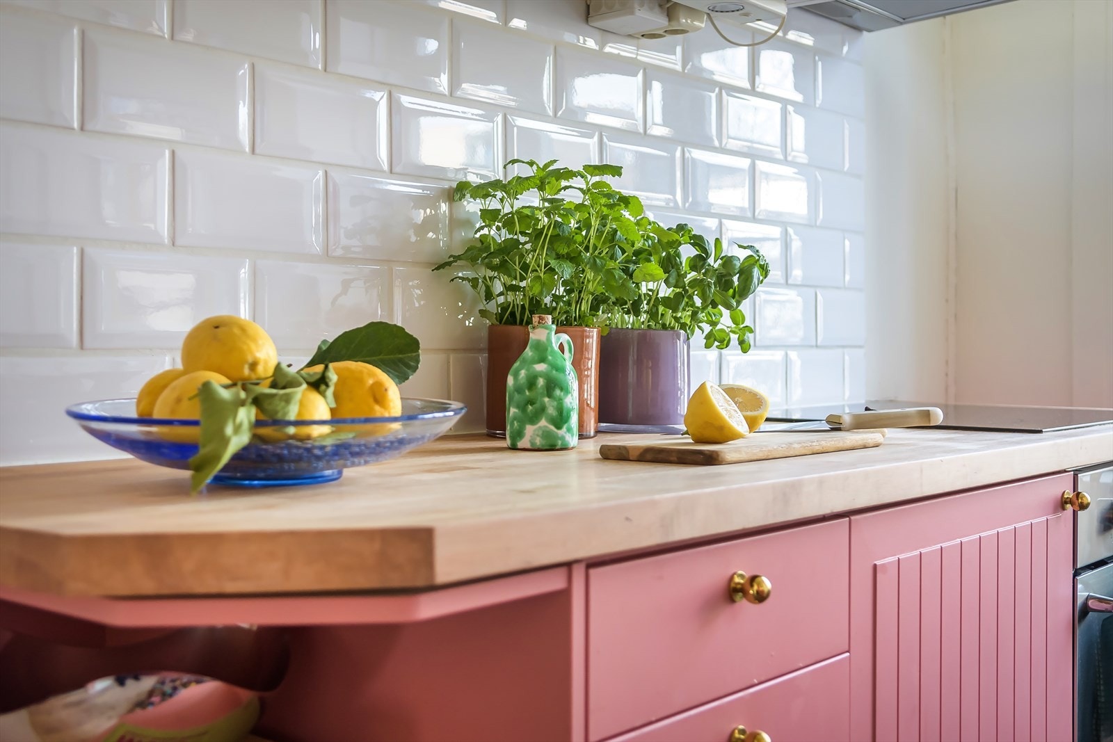 Lyst og innbydende innredning med stilige rosa skap, hvite fliser og en solid benkeplate. Perfekt for deg som elsker et personlig og inspirerende kjøkken. Galleribilde