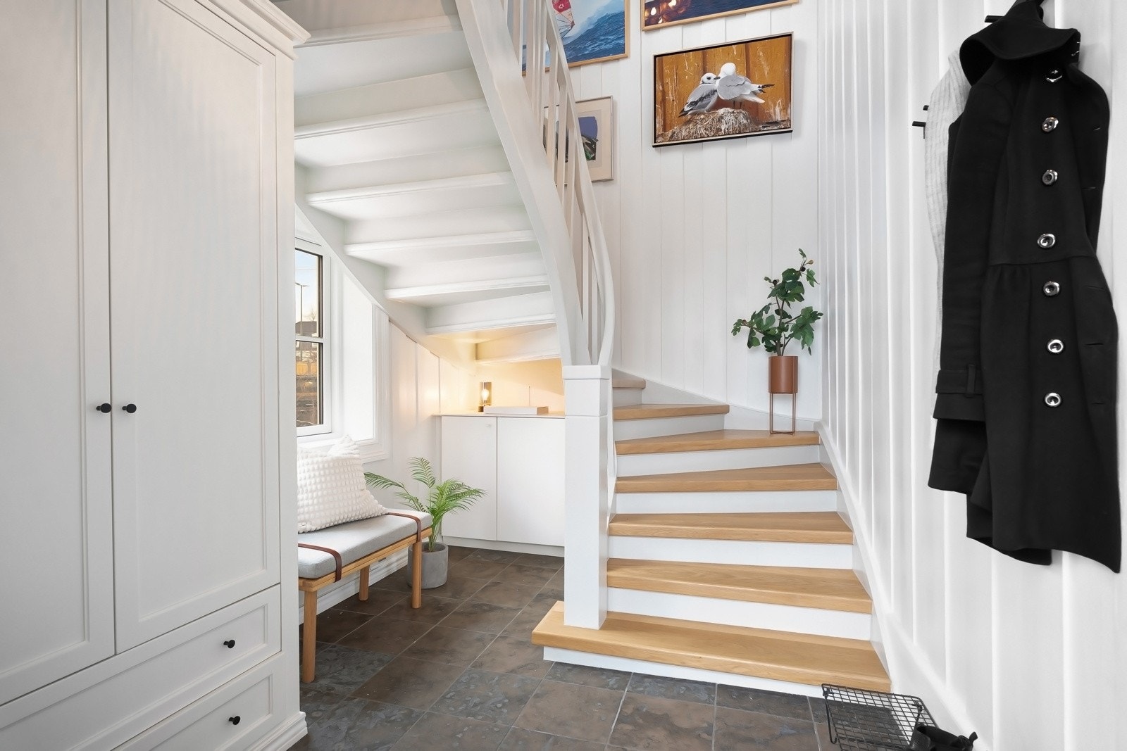 Inngangspartiet ble pusset opp i 2022 og entreen er innredet med et snekkerbygd garderobeskap, samt et benkeskap med skyvedører under trappen. Galleribilde