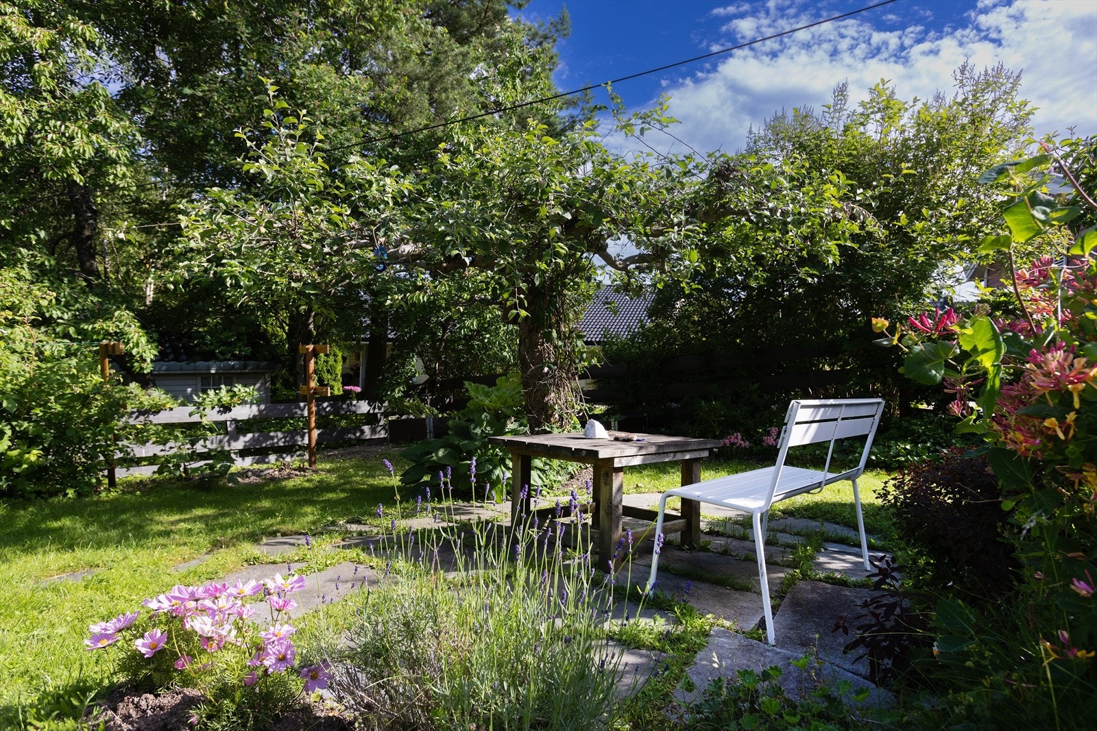 Boligen har en nydelig hage med pent anlagte bed for bærbusker og frukttrær, komplettert med elegante skiferfliser. Galleribilde