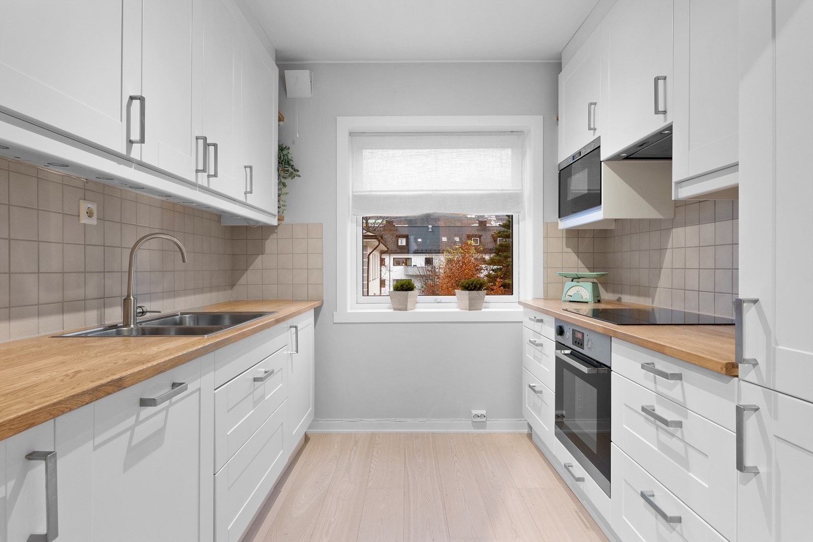 Pent kjøkken med hvite, profilerte fronter med heltre benkeplate. Galleribilde