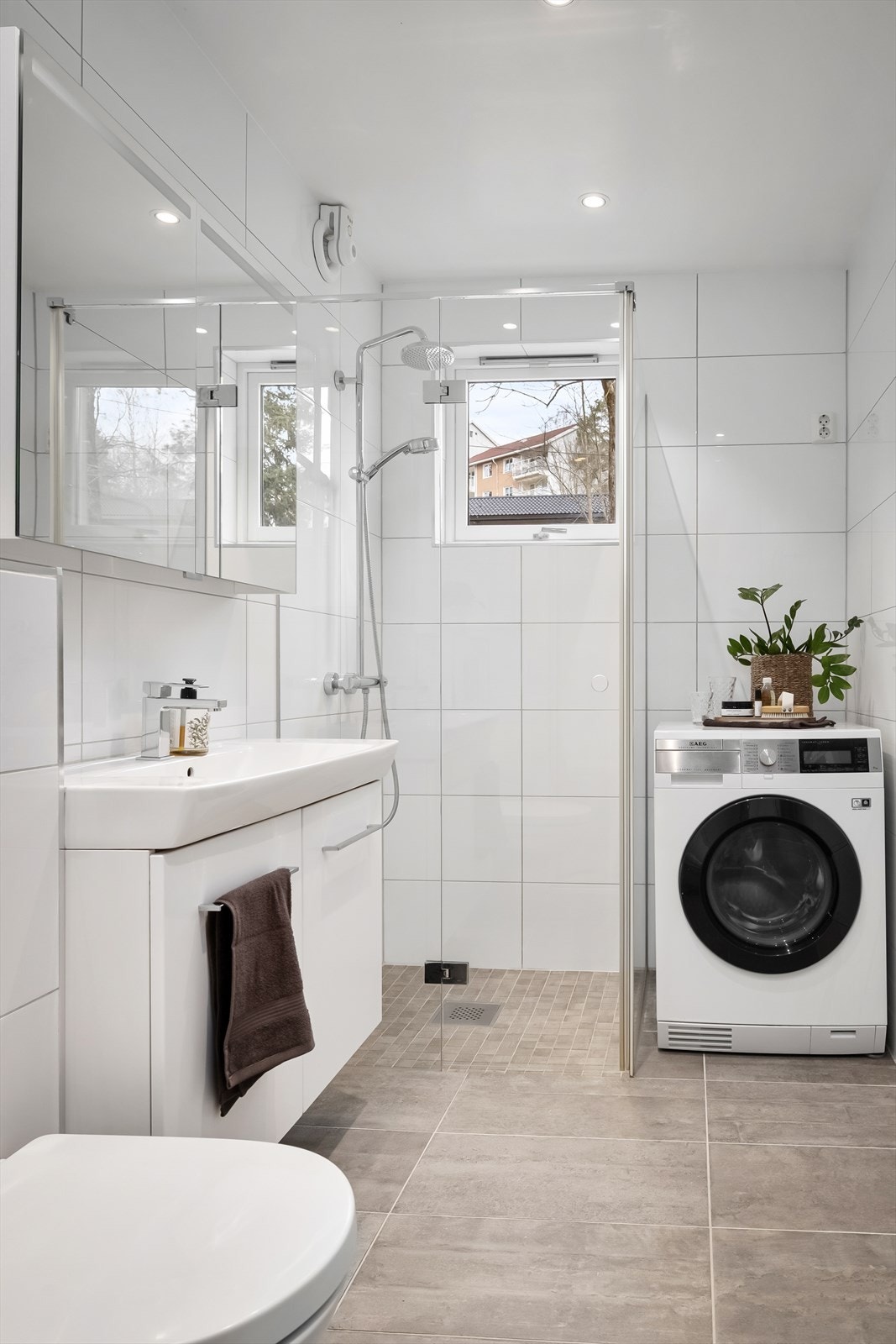 Baderomsinnredning med servantskap med ovenpåliggende servant og ett-greps armatur, speilskap med belysning og vegghengt toalett Galleribilde