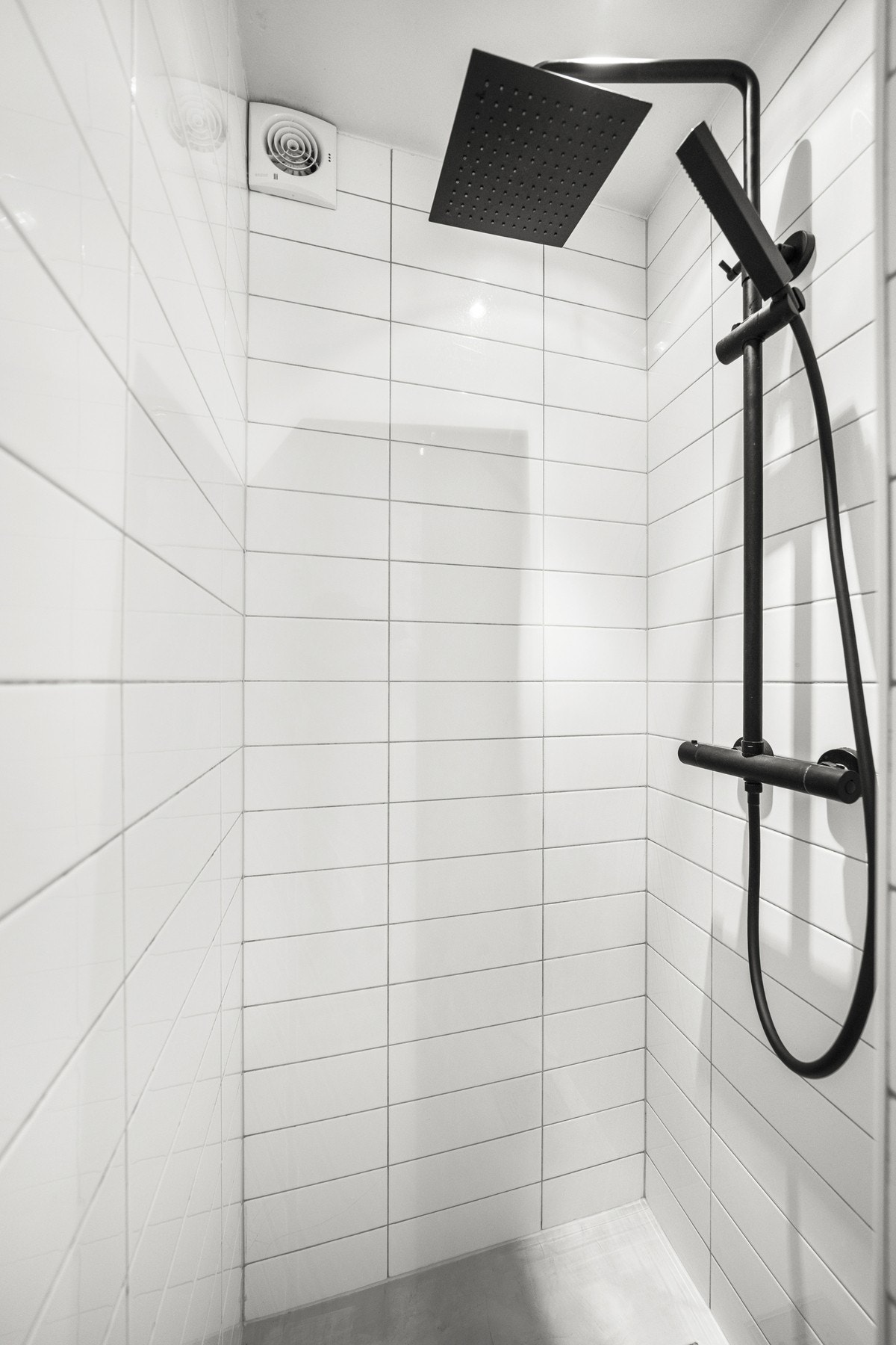 Her finner du et arealeffektivt oppsett med dusj rett på gulvet, vegghengt toalett og en servant med ett-greps blandebatteri, elegant nedfelt i en benk med mikrosement. Galleribilde