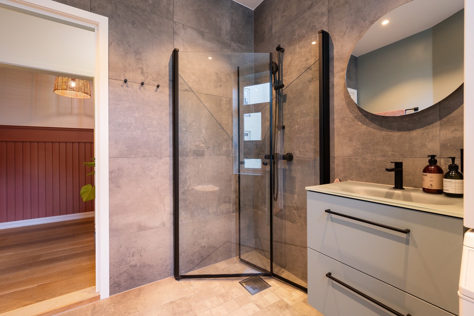 Gulvet har 60x60 cm fliser, mens dusjsonen har en nedsenket grube med mindre 10x10 cm fliser og lokalt fall mot sluk. Dusjen er utstyrt med herdet glassdører. Galleribilde