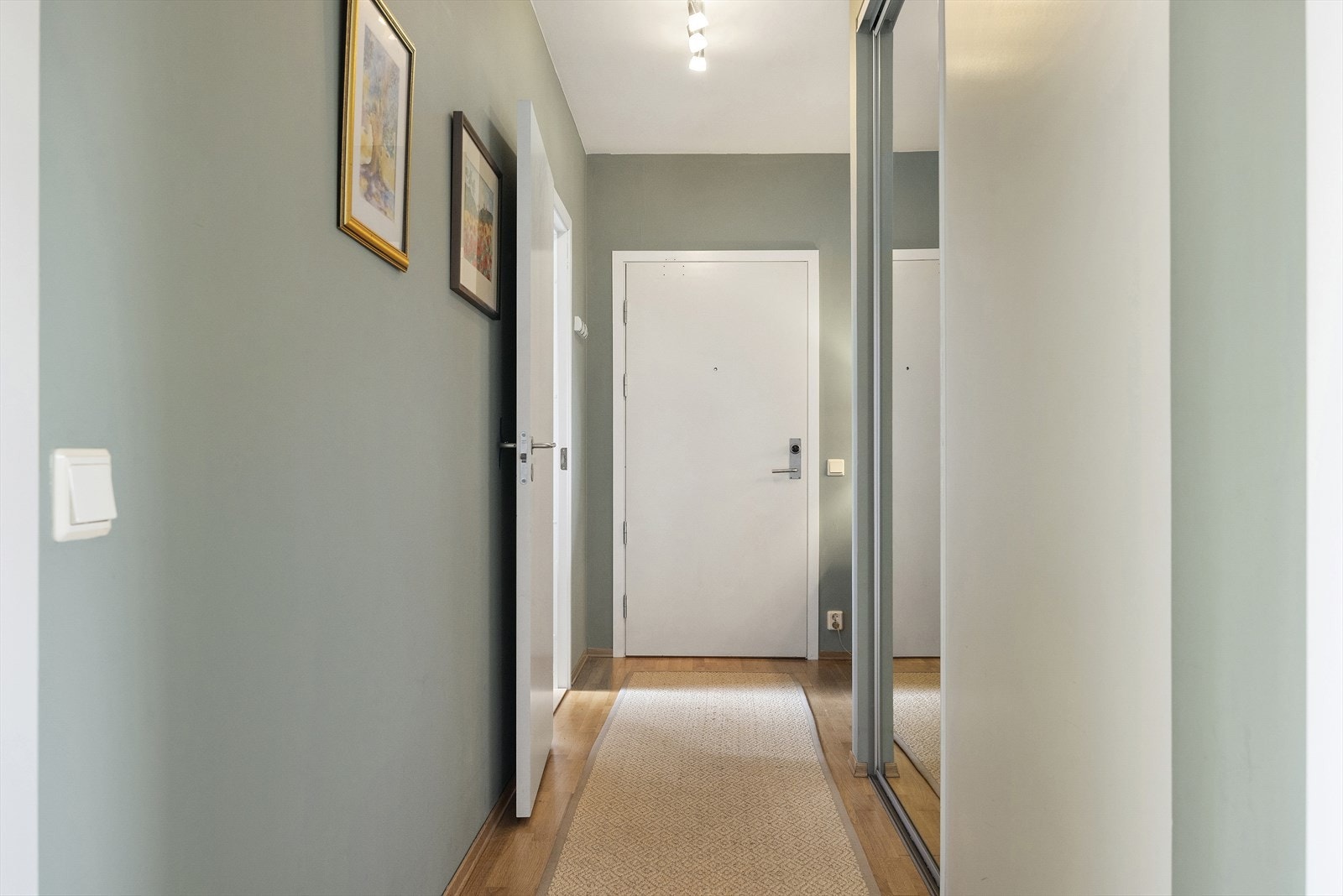 Leiligheten har en innbydende entré som skaper et umiddelbart godt førsteinntrykk. Det er god plass til oppbevaring av yttertøy i den romslige skyvedørsgarderoben. Galleribilde